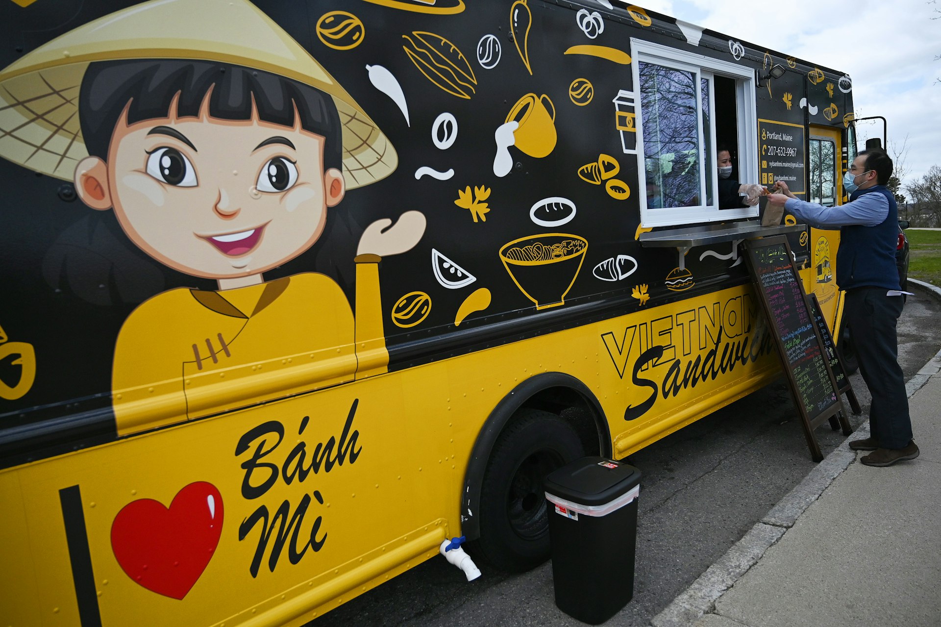 Phan serves a customer at Vy Banh Mi food truck, Portland, Maine, USA