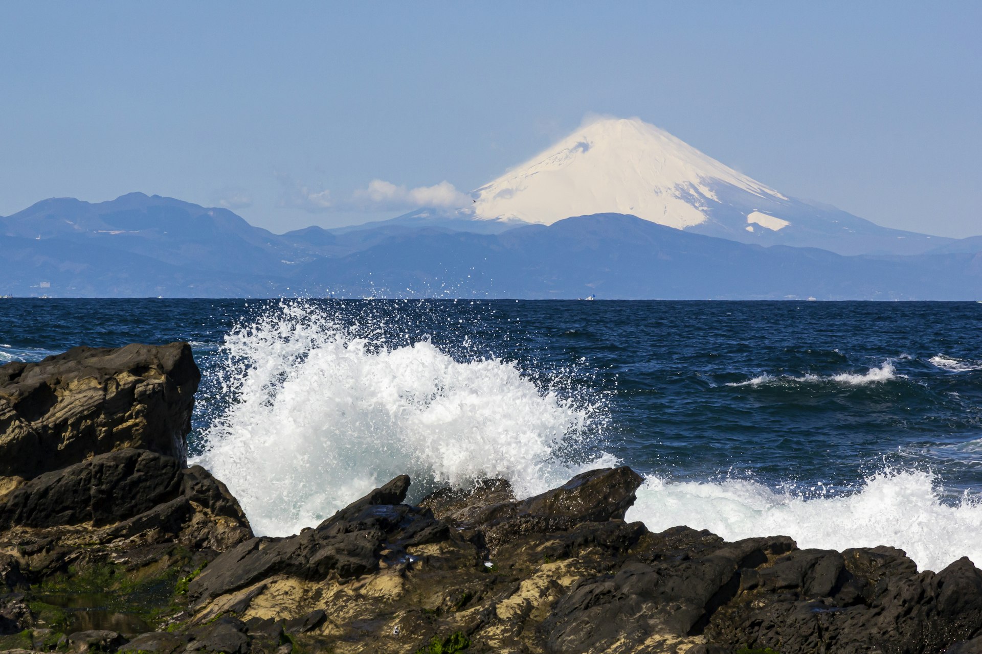 Waves hit Shonan Beach with a view of snow-capped Mt Fuji in the distance, Misaki, Jogashima, Kanagawa, Japan