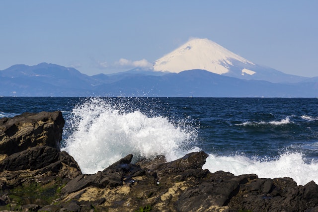 Waves hit Shonan Beach with a view of snow-capped Mt Fuji in the distance, Misaki, Jogashima, Kanagawa, Japan