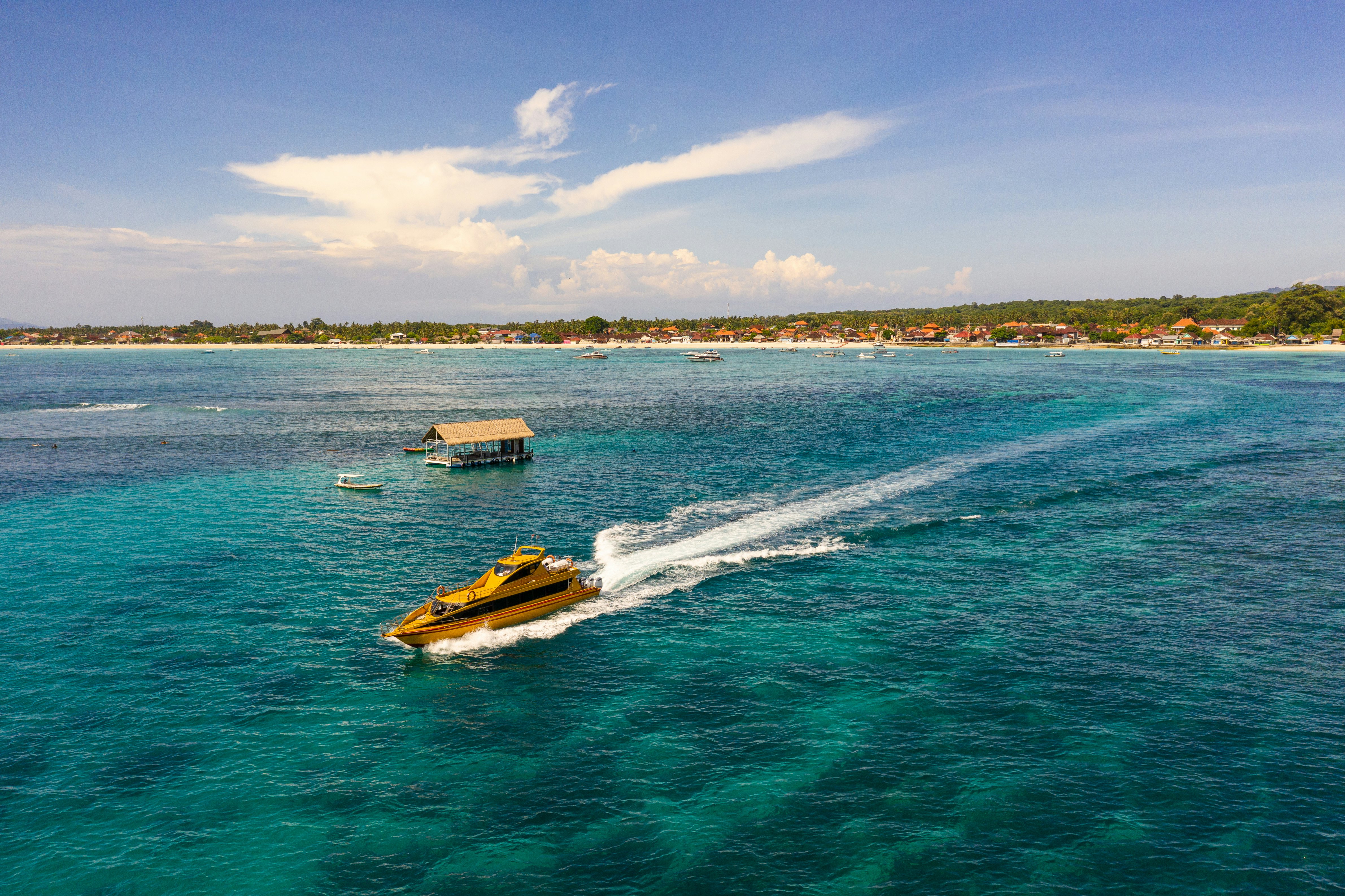 A fast-boat service leaves Nusa Lembongan in Bali, Indonesia, leaving a white trail in the water.