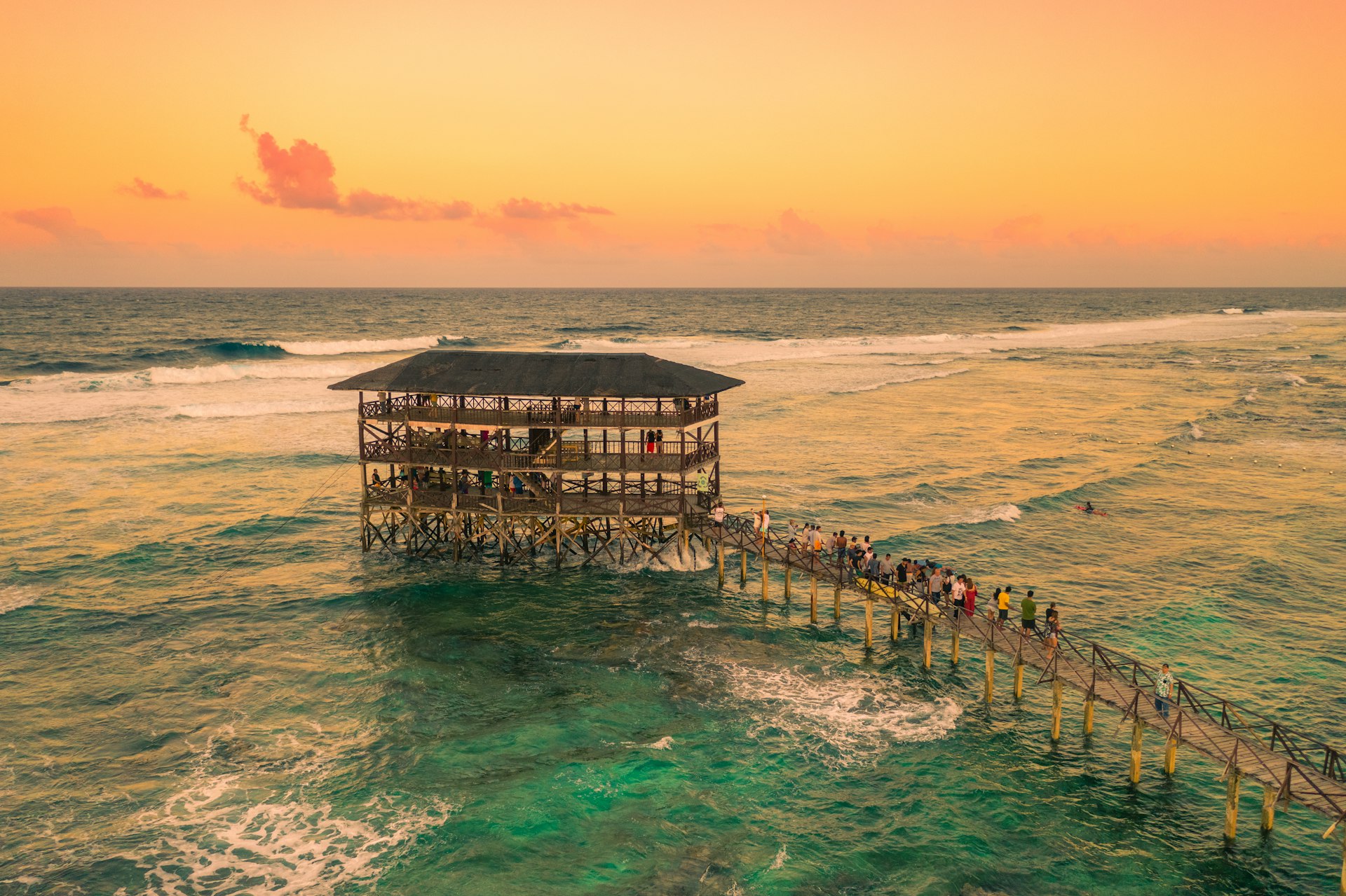 A large multi-level wooden structure and walkway our to sea near a surf spot
