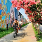 In Atlanta, United States people bike along a sidewalk lined with painted murals in Inman Park by the Beltline trail. © Boogich / Getty Images