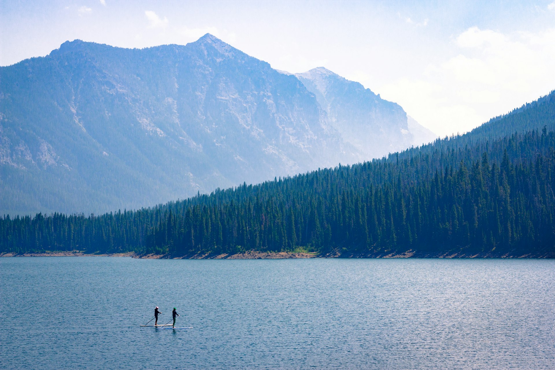 Paddle boarders drift through the Hyalite Reservoir on a sunny day in Montana.