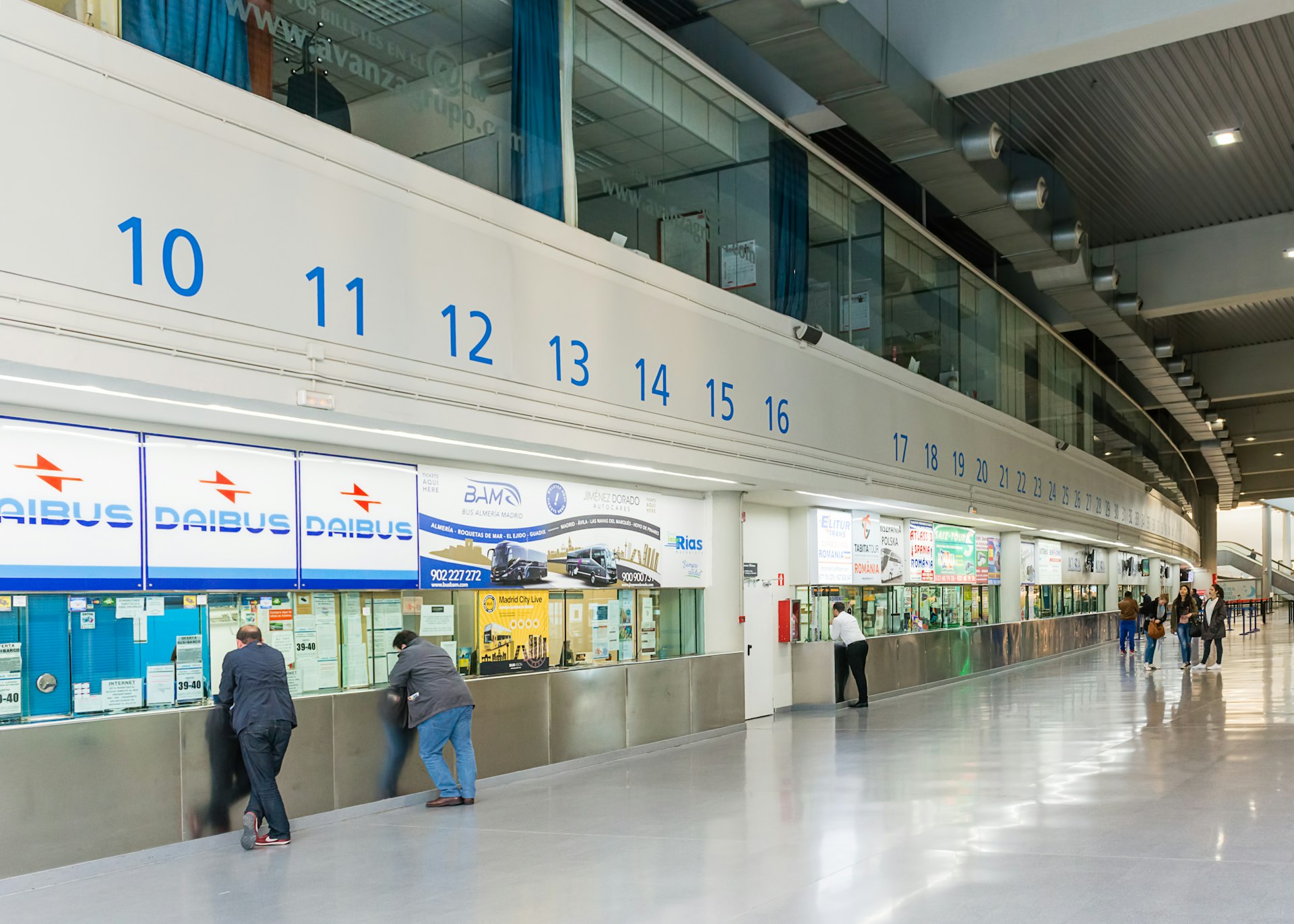 A long stretch of ticket counters for different bus companies at a huge bus station in Madrid, Spain