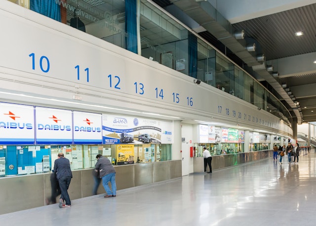 A long stretch of ticket counters for different bus companies at a huge bus station in Madrid, Spain