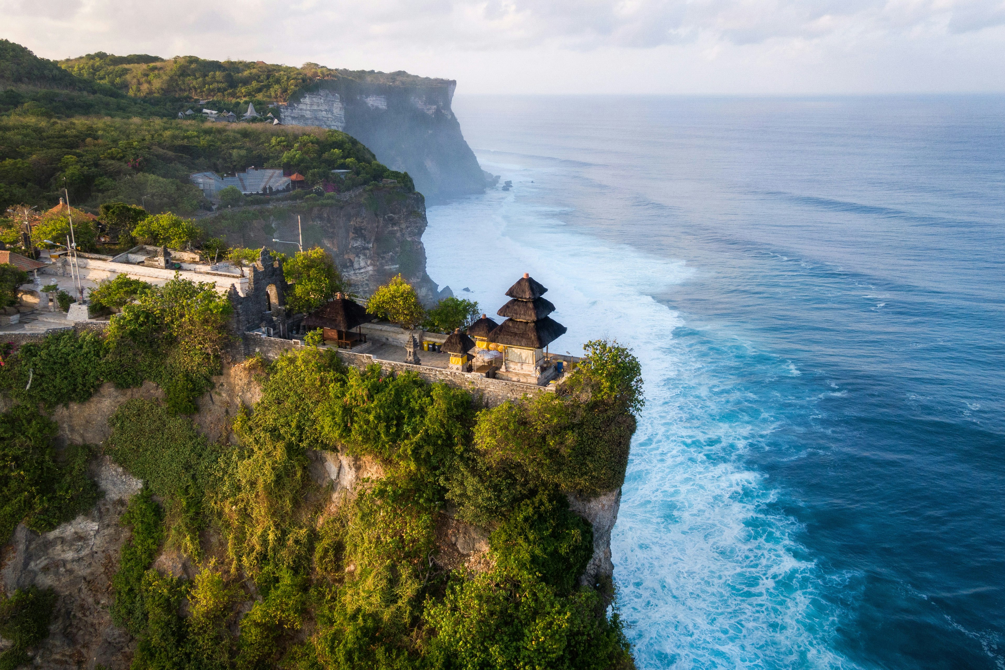 A clifftop temple surrounded by the ocean on a sunny day