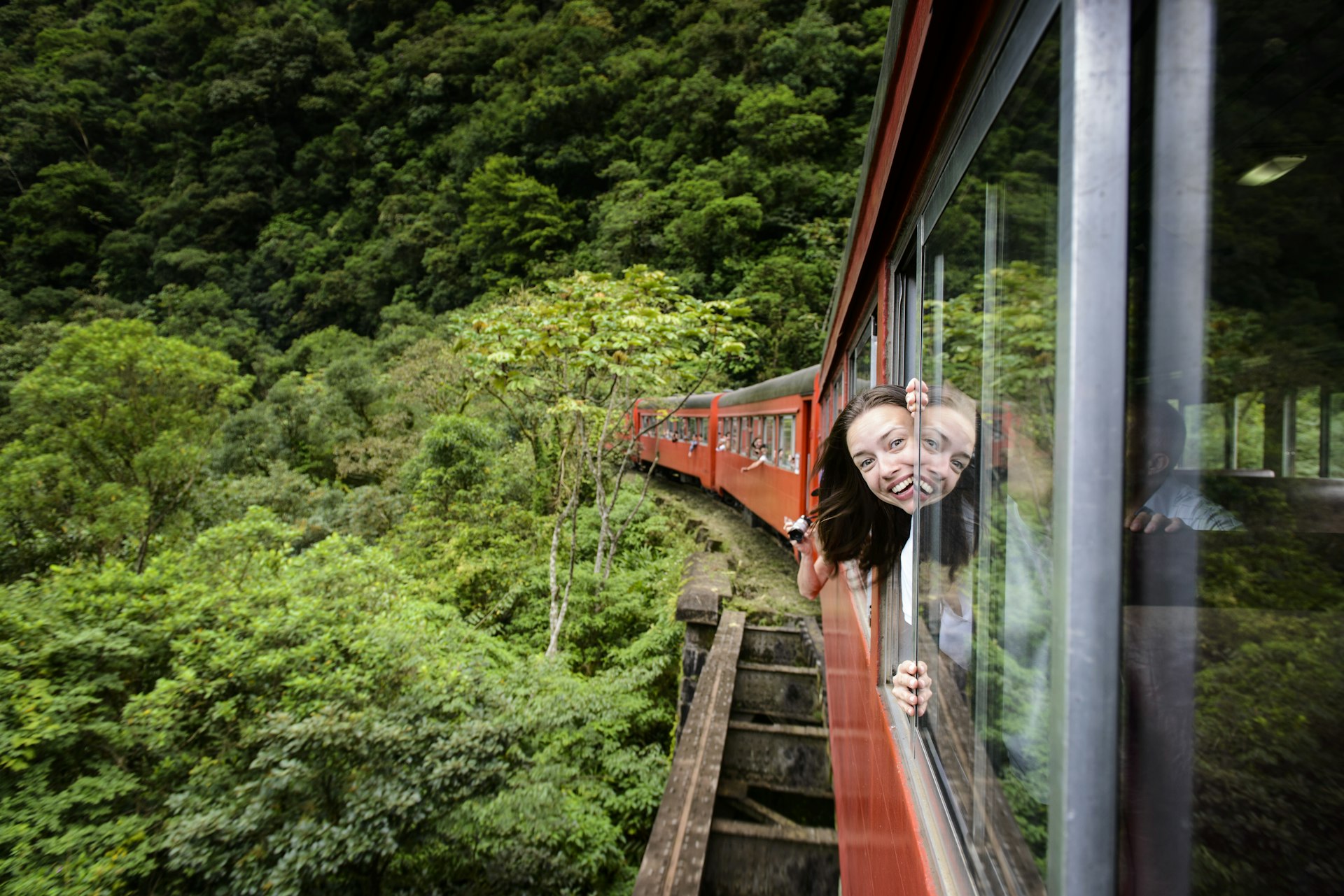 A woman sticks her head out of the window on the Serra Verde Express train from Curitiba to Morretes, Paraná, Brazil