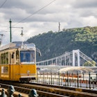 Horizontal Outdoors Europe Hungary Cable Car Train - Vehicle Cloud - Sky River Hill Day Budapest Elizabeth Bridge Railroad Track Danube River Number 2 No People Photography Gellert Hill
Tram running along the Danube in Budapest with Szent Gellert hill in the background.