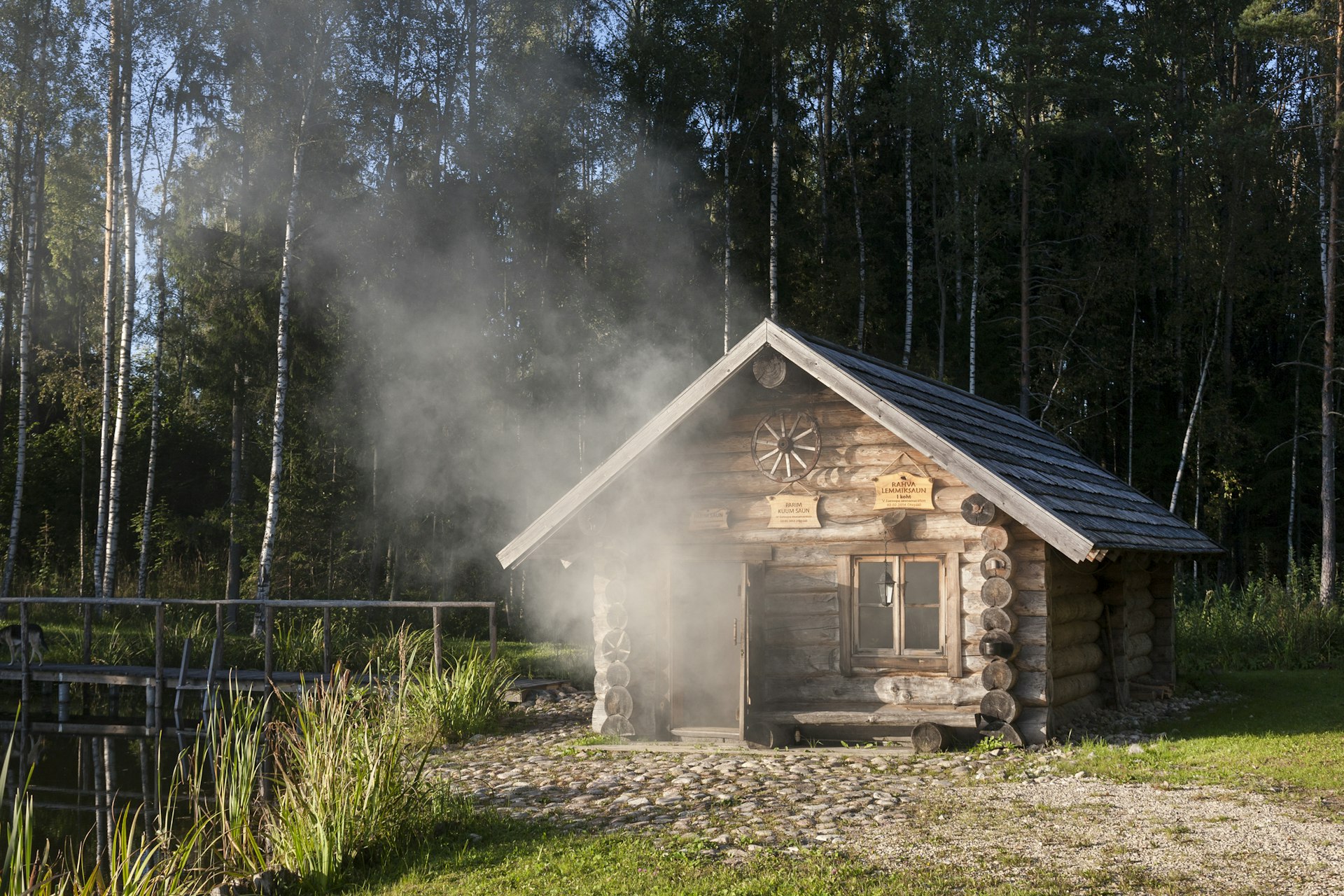 A small wooden cabin with smoke and steam coming out the open door