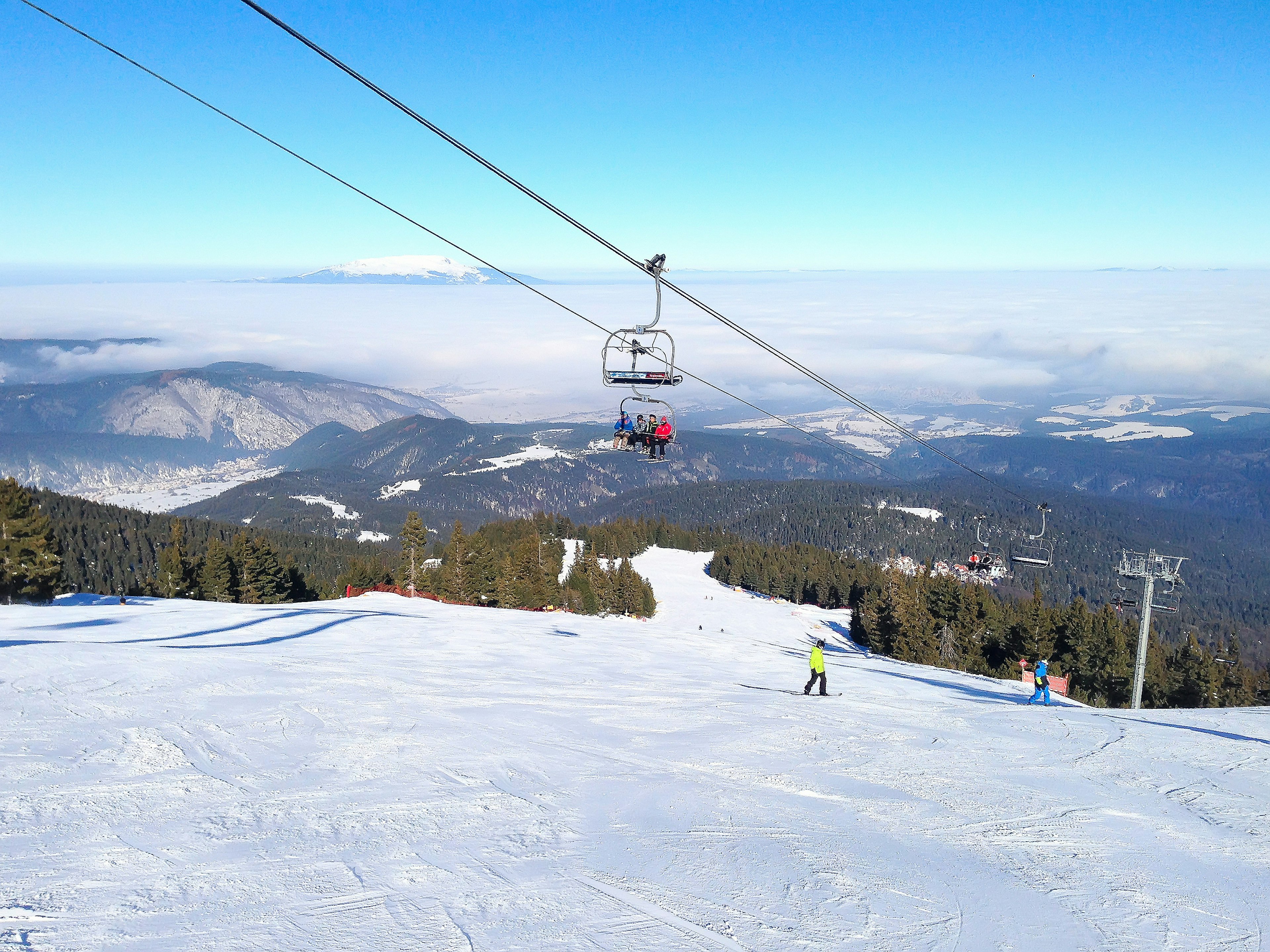 A ski slope covered in snow, with a chairlift passing overhead.