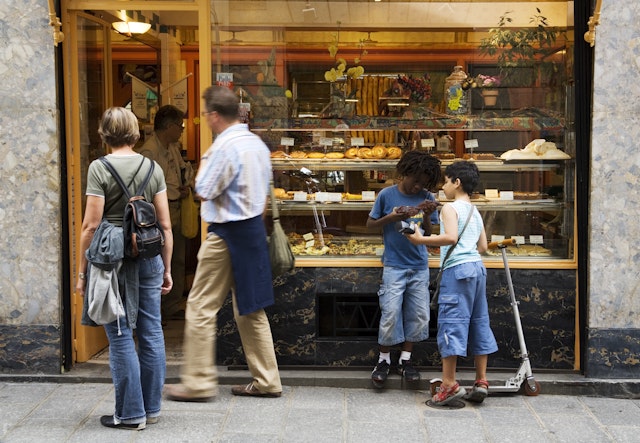 People standing outside of a bakery window in France