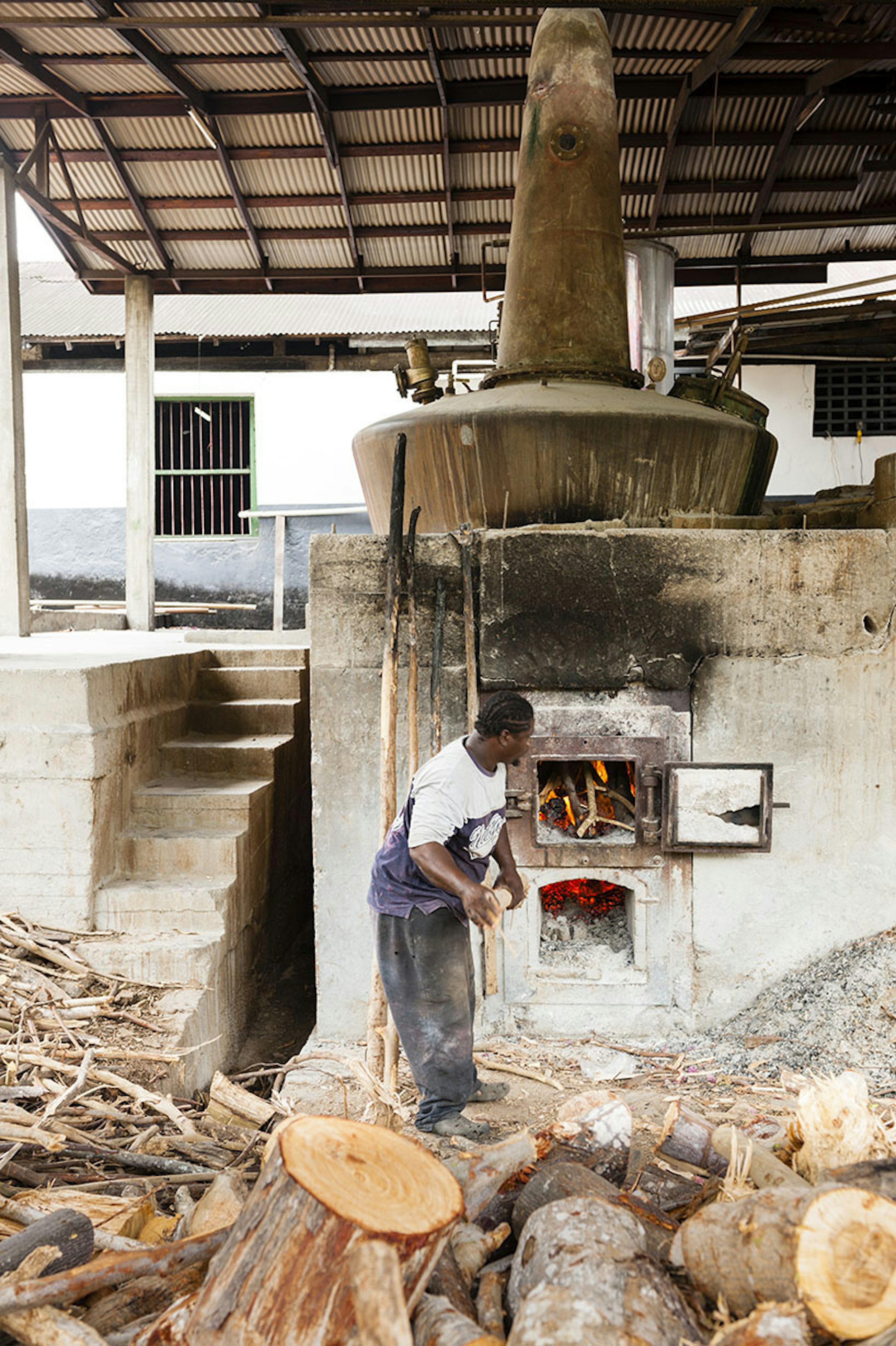 Man stoking fire at River Antoine Rum Distillery in Grenada