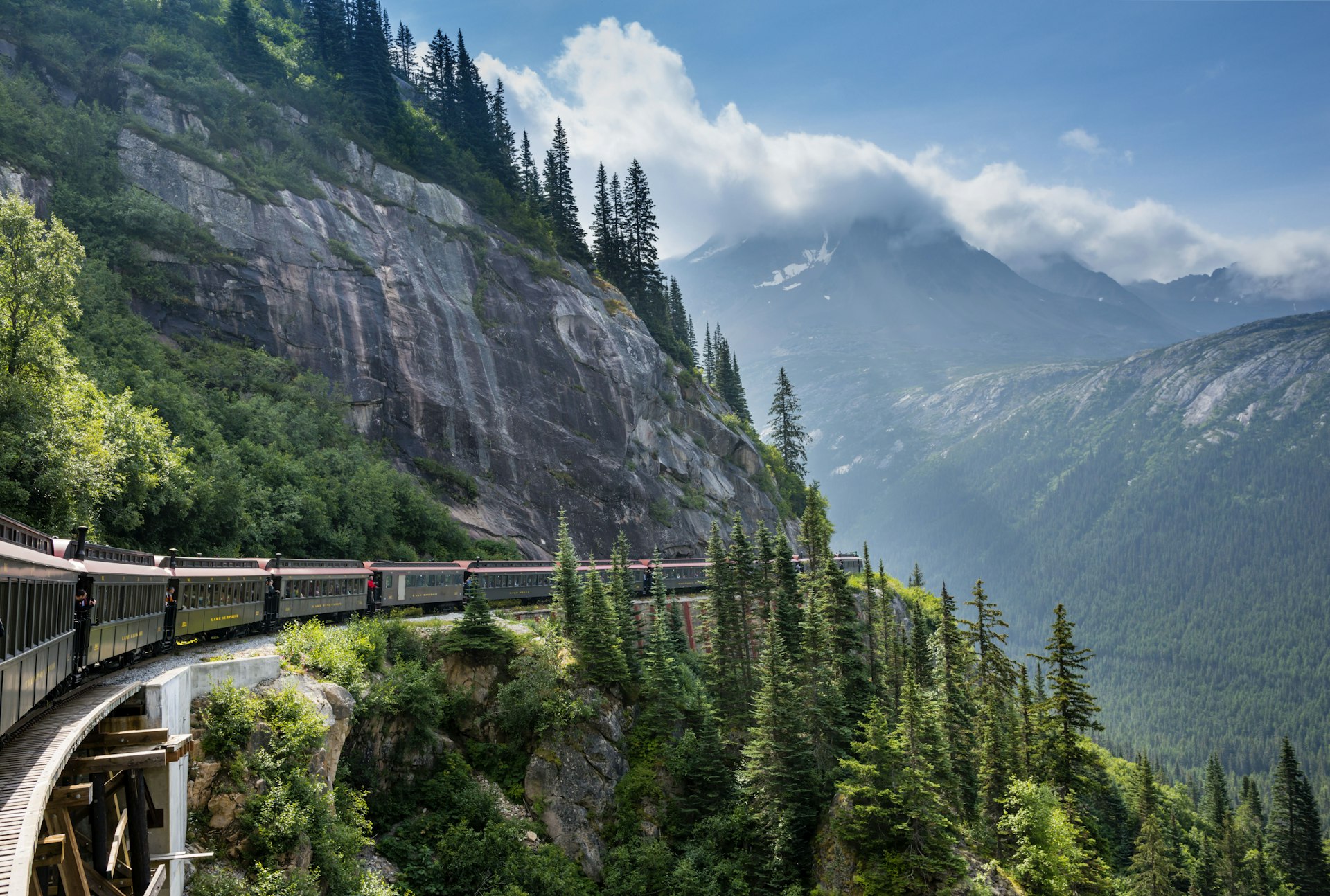 A heritage train hugs the cliff edge in a mountainous area