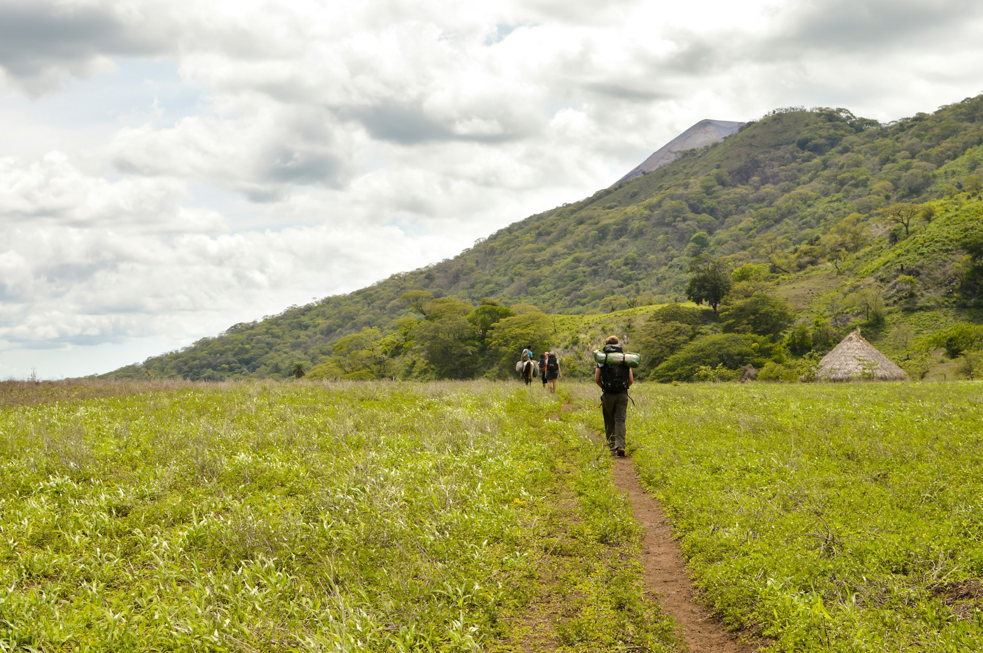 Group of hikers walks through the field and is about to ascend the slopes of the very active Telica volcano in San Jacinto, Leon, Nicaragua. Central America