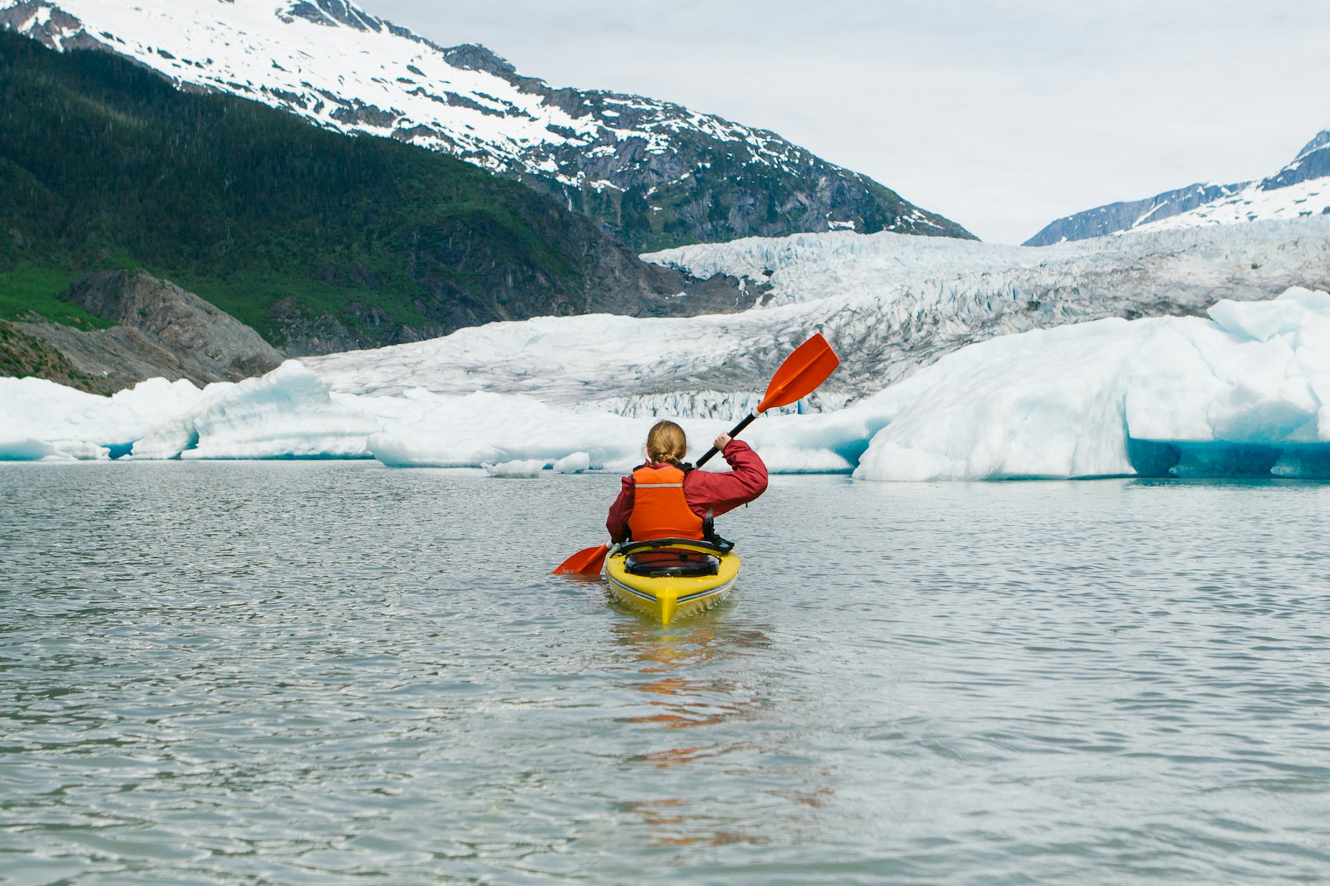 woman kayaking solo by a glacier in Alaska