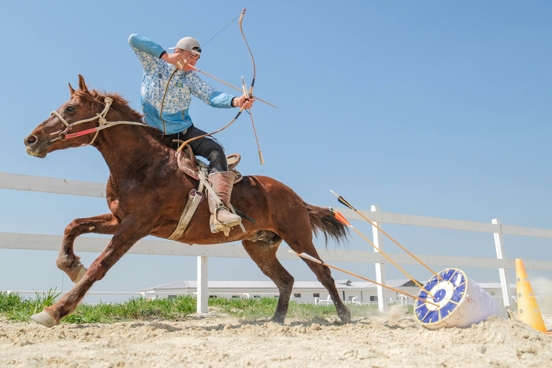 A horseback rider fires and arrow at a target while riding past at speed