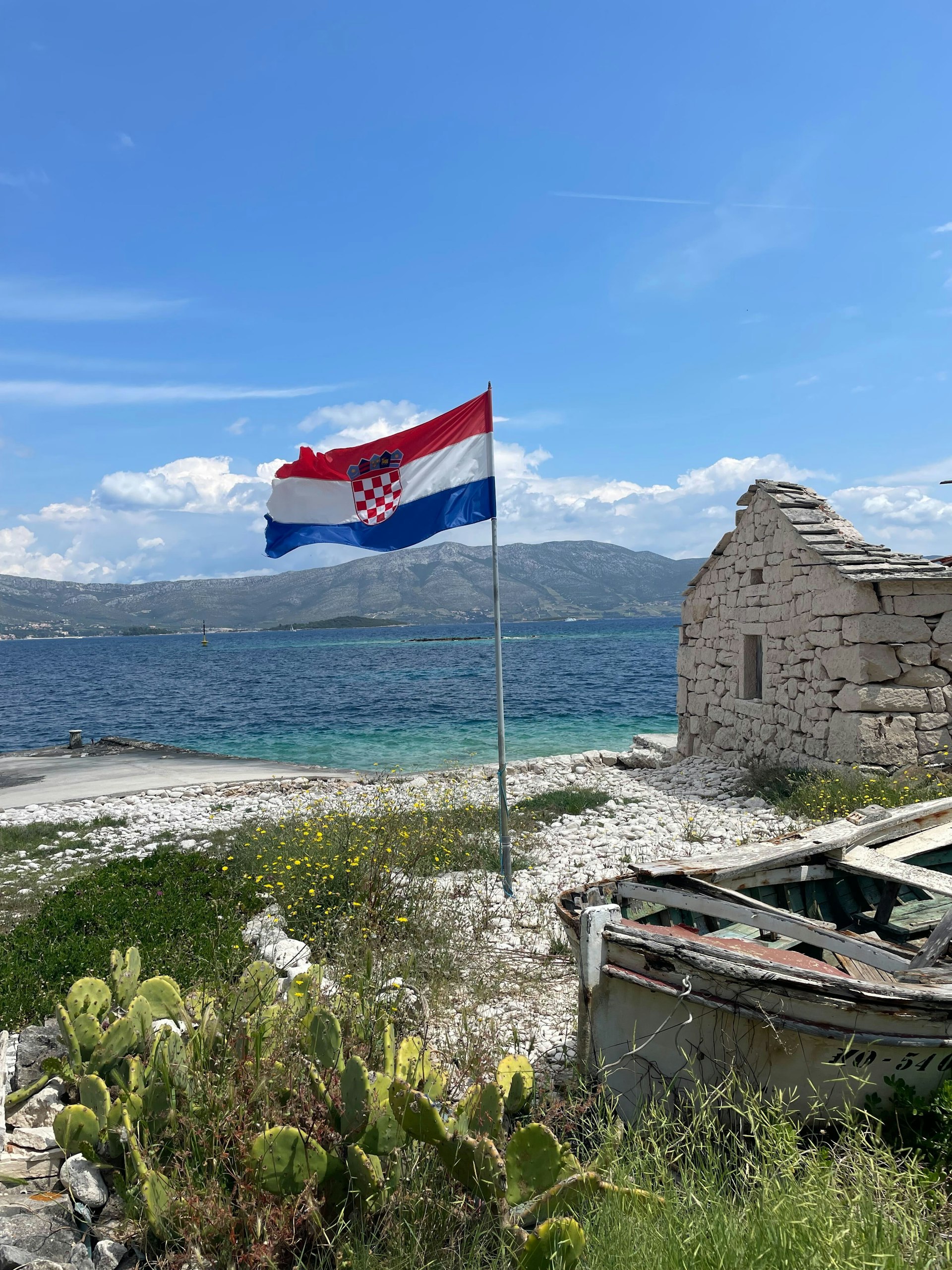 A red white and blue Croatian flag flies on a beach