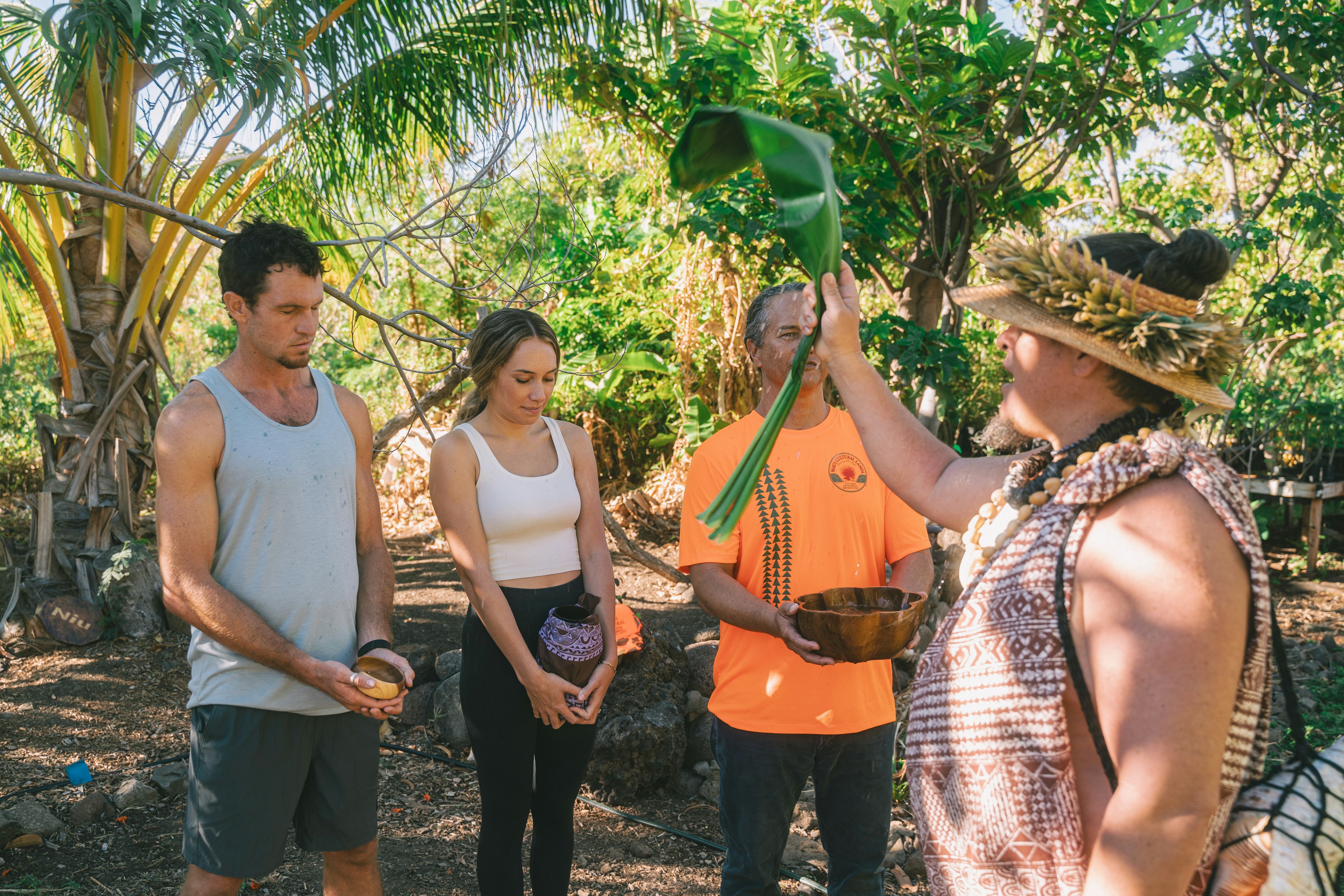 A tourist guide holds up a large leaf to a group of tourists