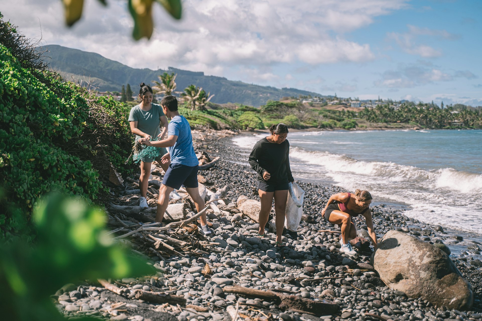 Volunteer tourists pick up trash on a rocky beach