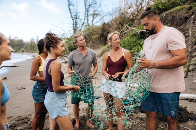 A guide shows volunteer tourists the risks of nets abandoned on beaches