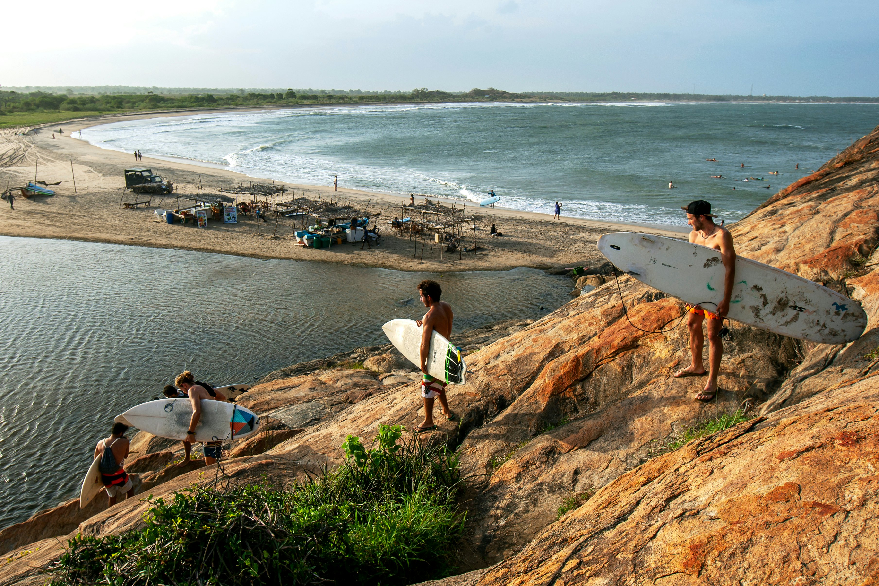 A group of surfers climb down Elephant Rock towards the beach for a surfing session.