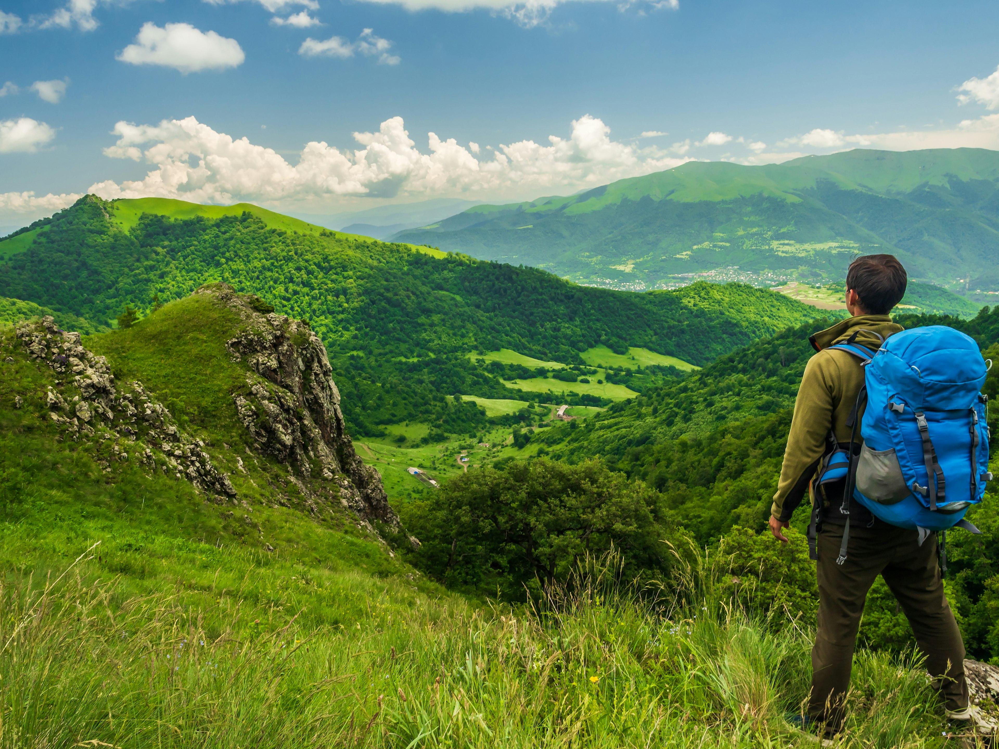 A hiker looks out at the green hills and valley beyond, Dilijan National Park, Armenia