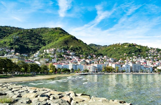 The rocky shore of a seaside town backed by buildings built into the steep hillside