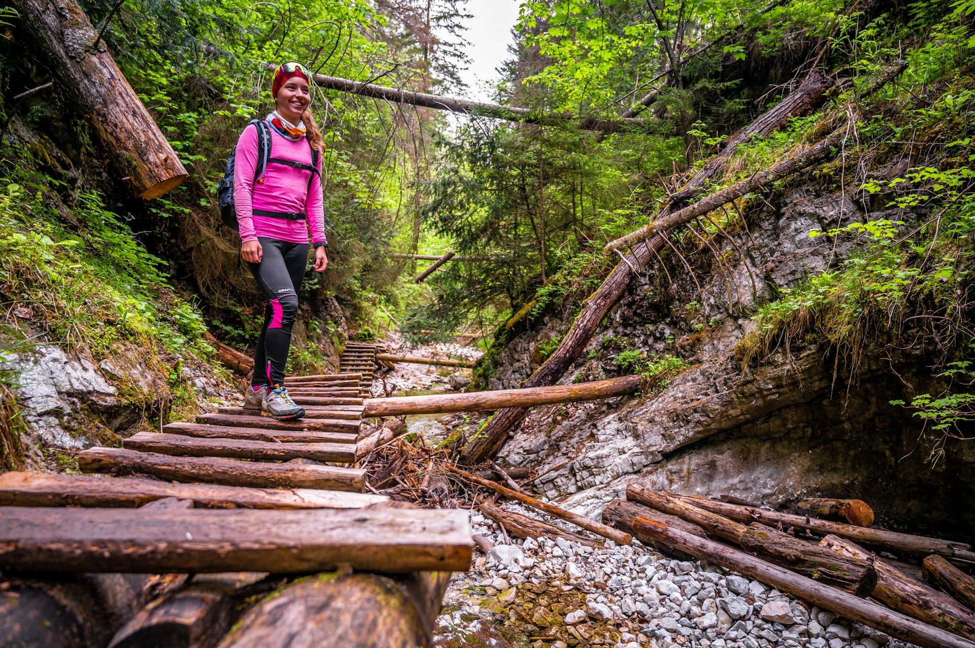 A woman on a ladder by a waterfall at Slovensky Raj National Park, Slovakia