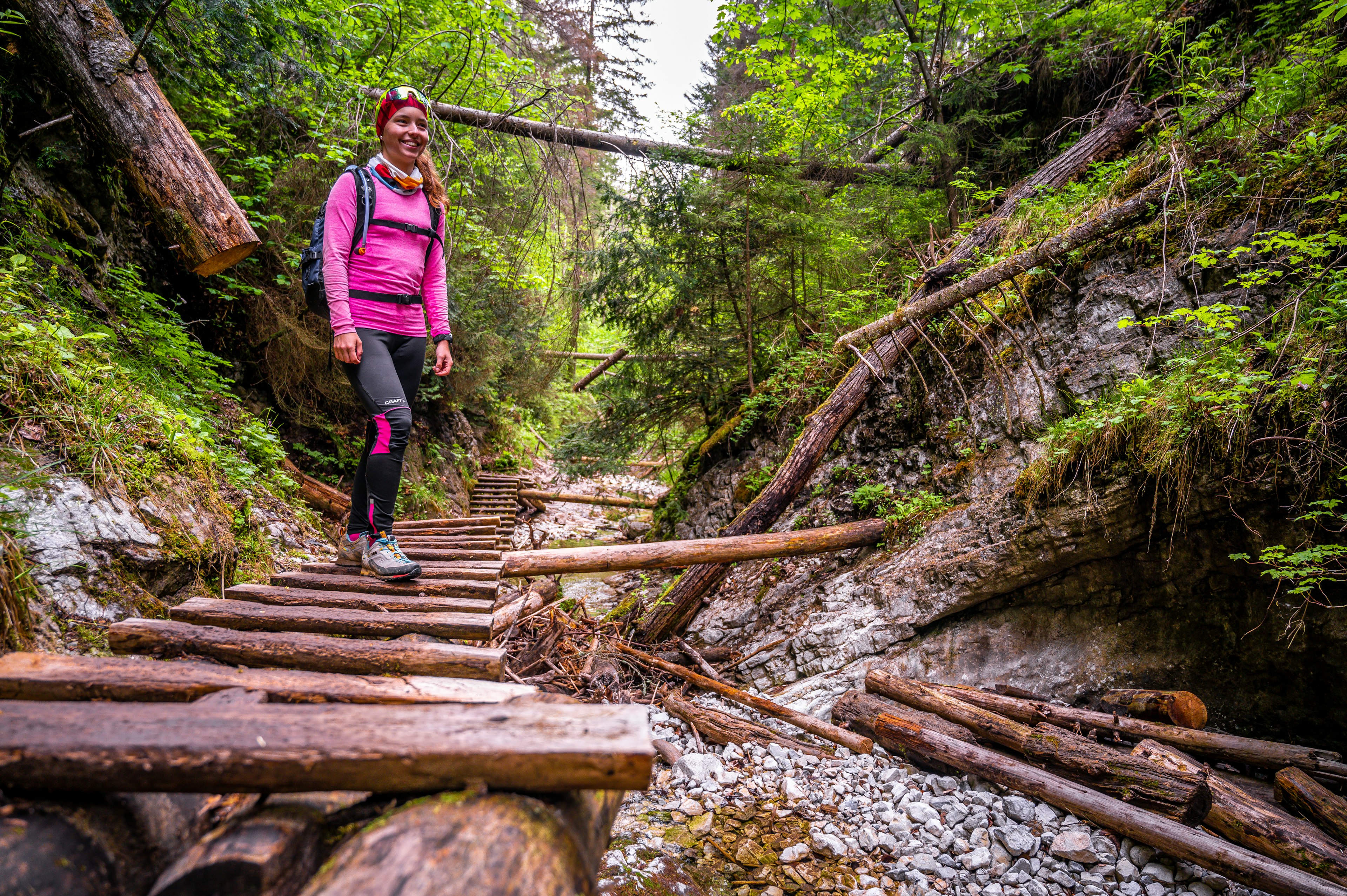 A woman on a ladder by a waterfall at Slovensky Raj National Park, Slovakia