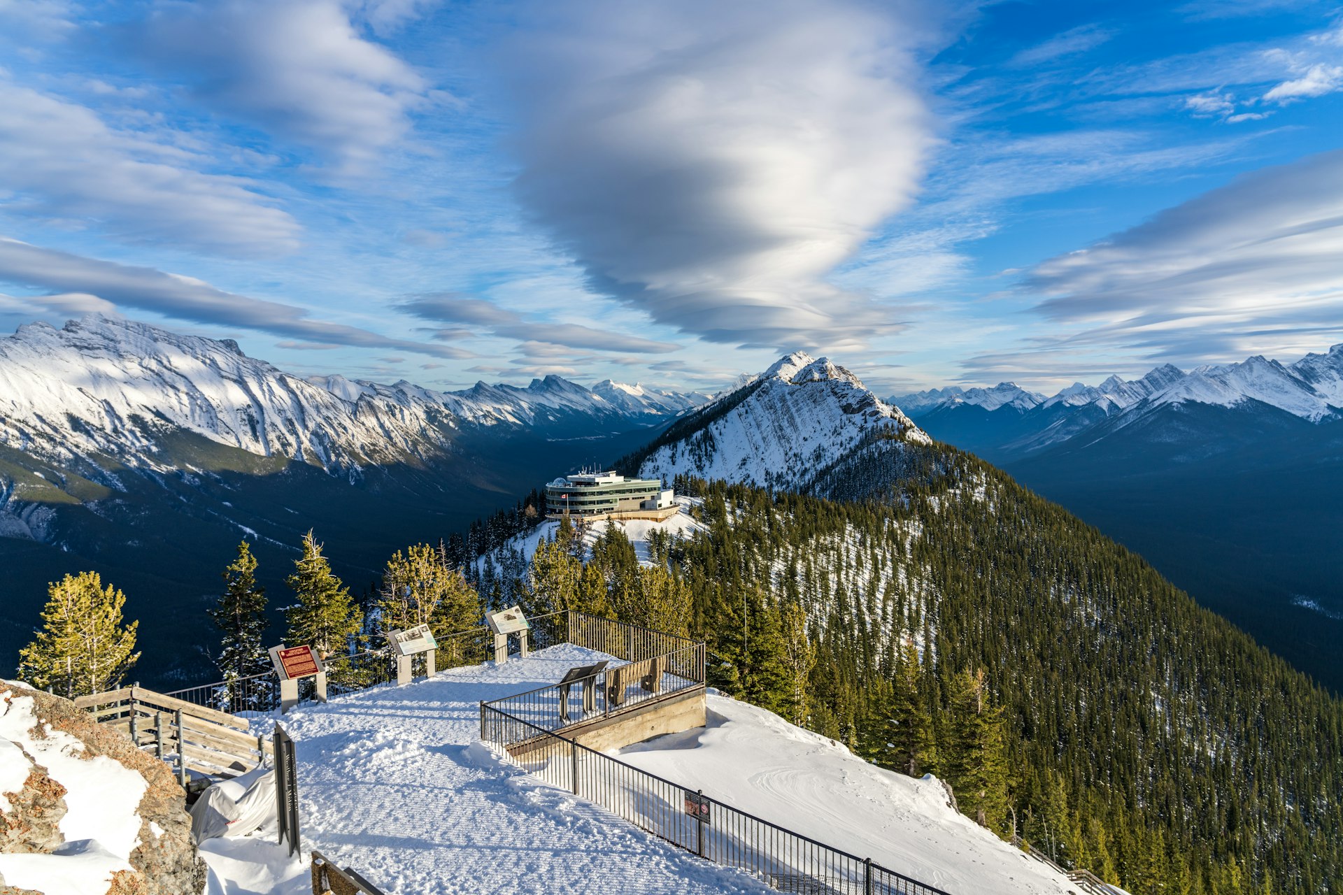 Wooden stairs and boardwalks are covered with snow; the viewing platform overlooks Banff Gondola Station