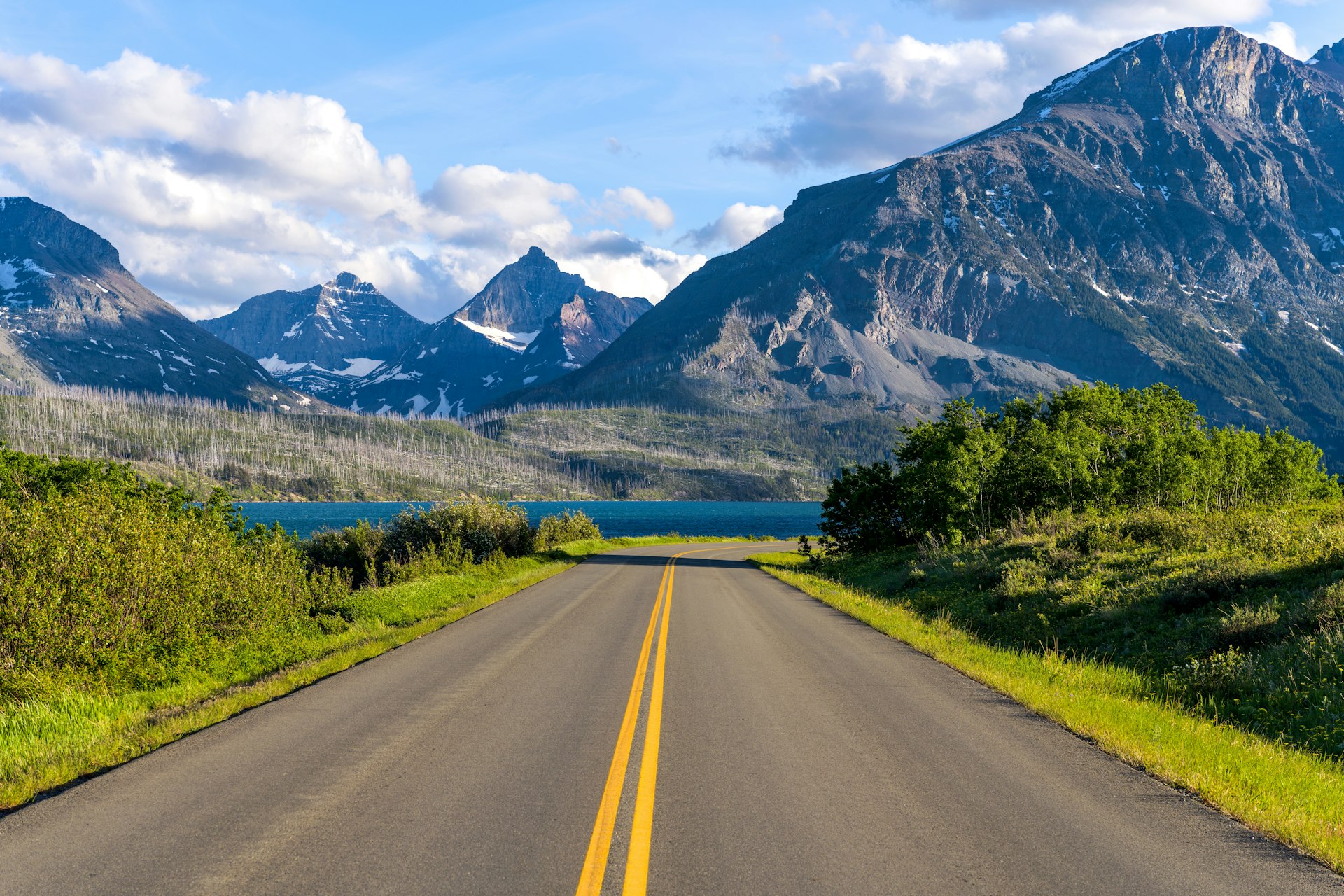 A road in a mountainous area descends towards a lake