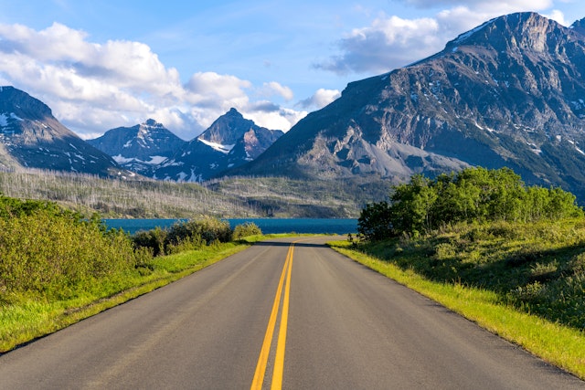 A road in a mountainous area descends towards a lake