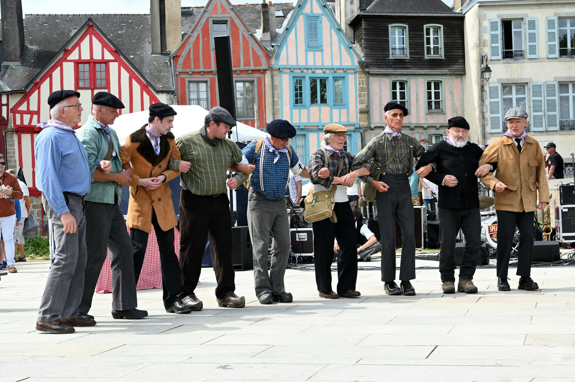 A row of older men wearing similar outfits stand together as part of a dance performance