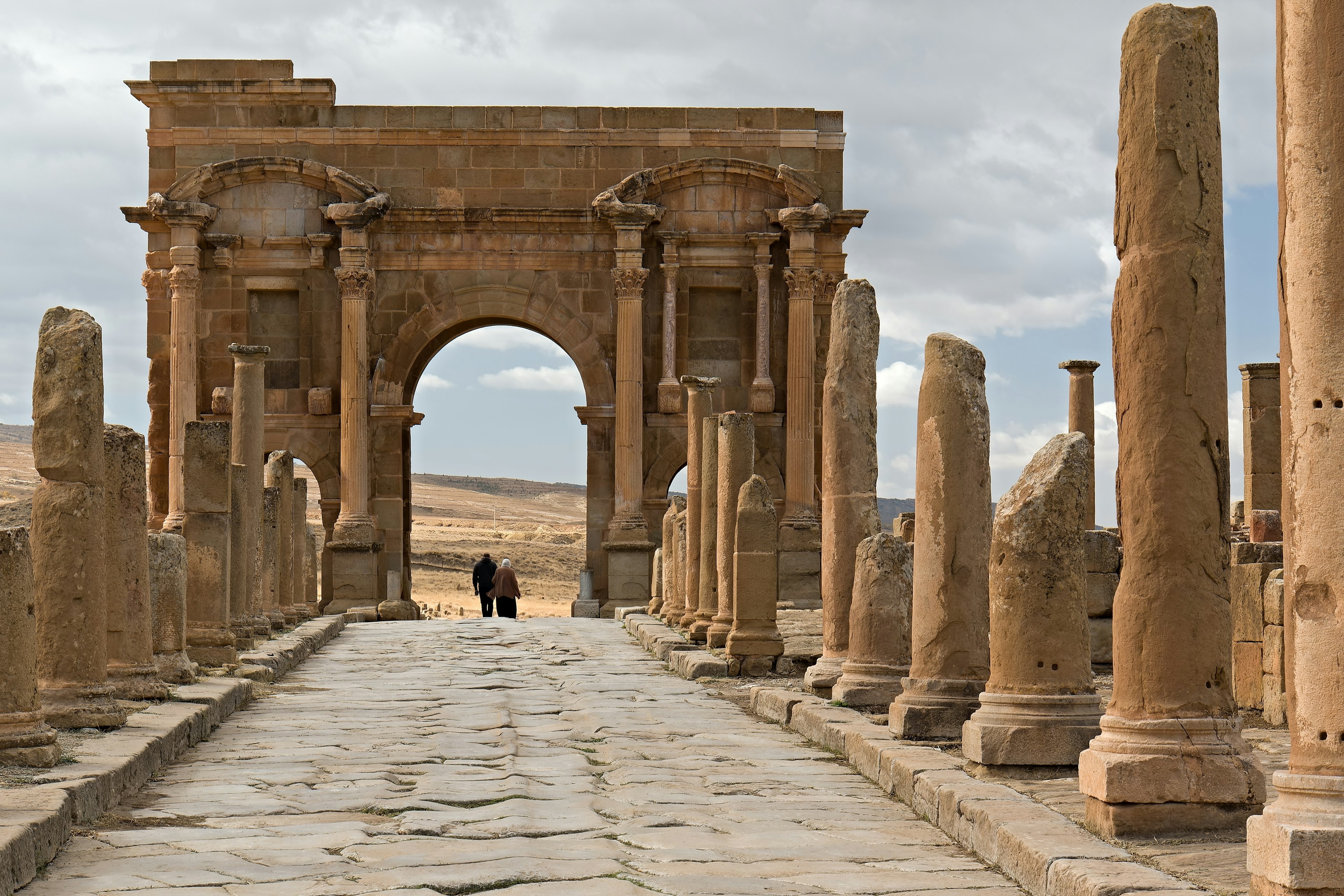 People walk by the Arch of Trajan in the ruins of Timgad, Algeria