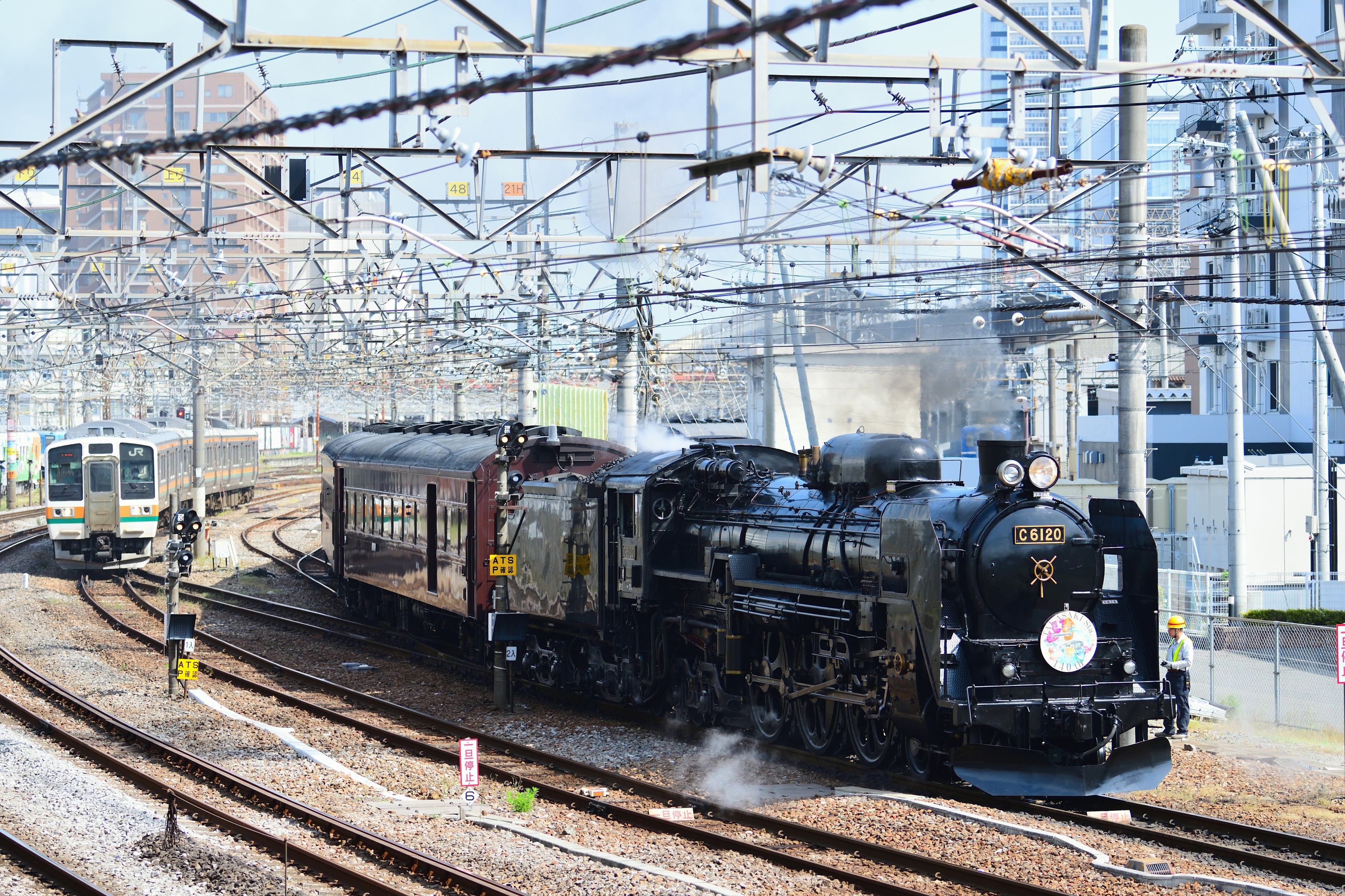 A vintage steam locomotive pulls an carriages beside a modern train in Gunma, Japan.