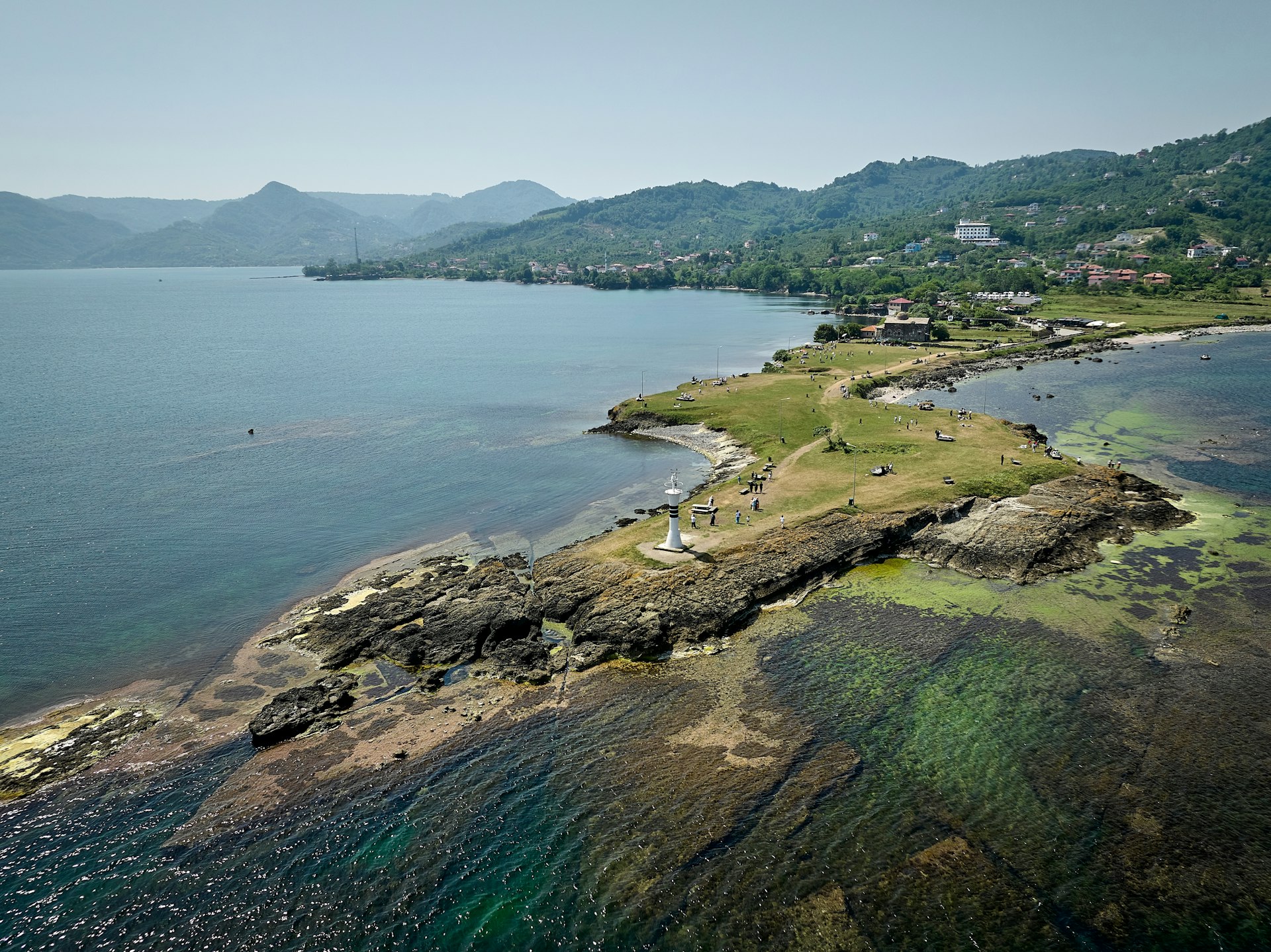 A narrow peninsula, with a white lighthouse at its tip, stretches out to sea