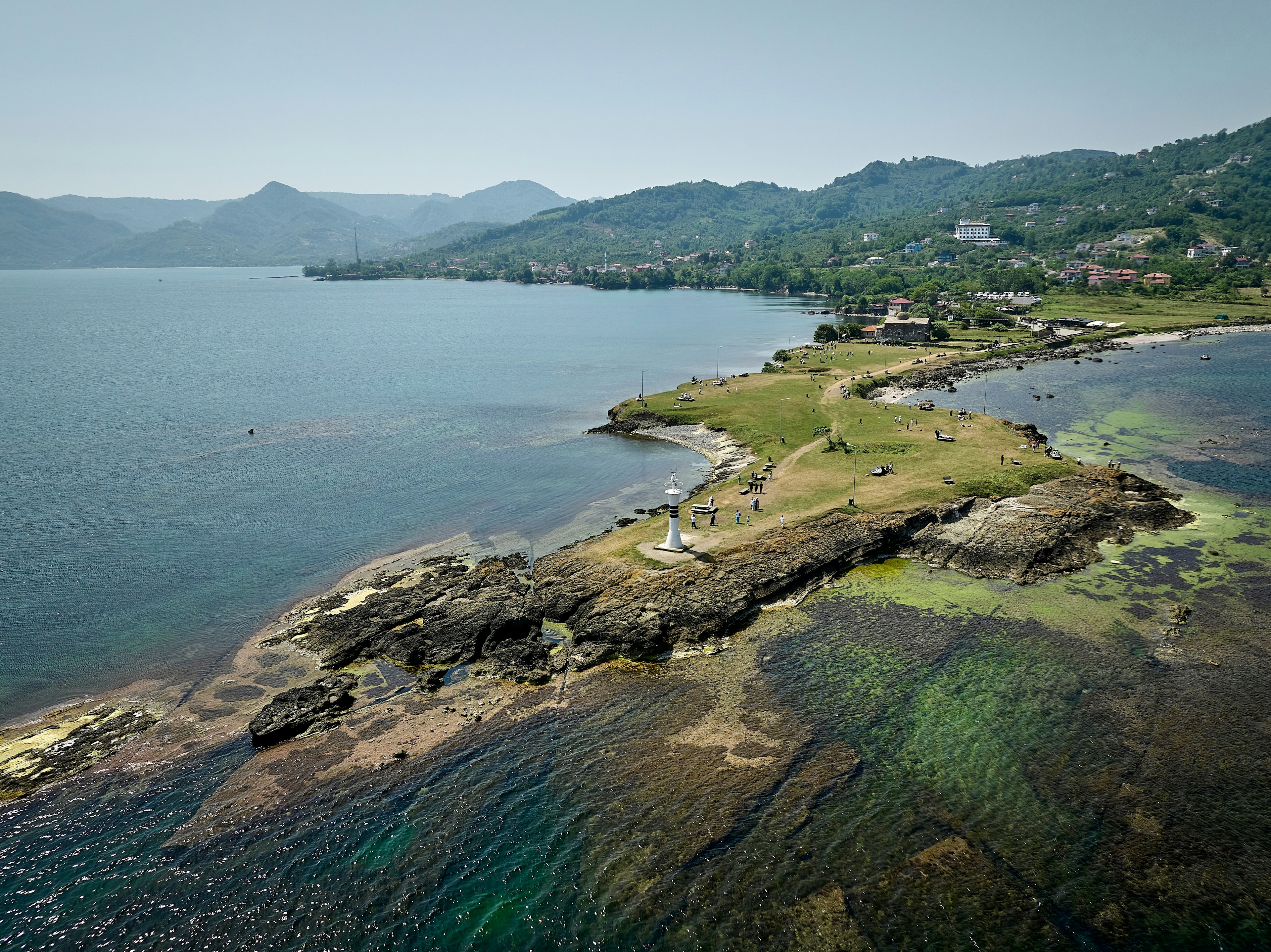 A narrow peninsula, with a white lighthouse at its tip, stretches out to sea