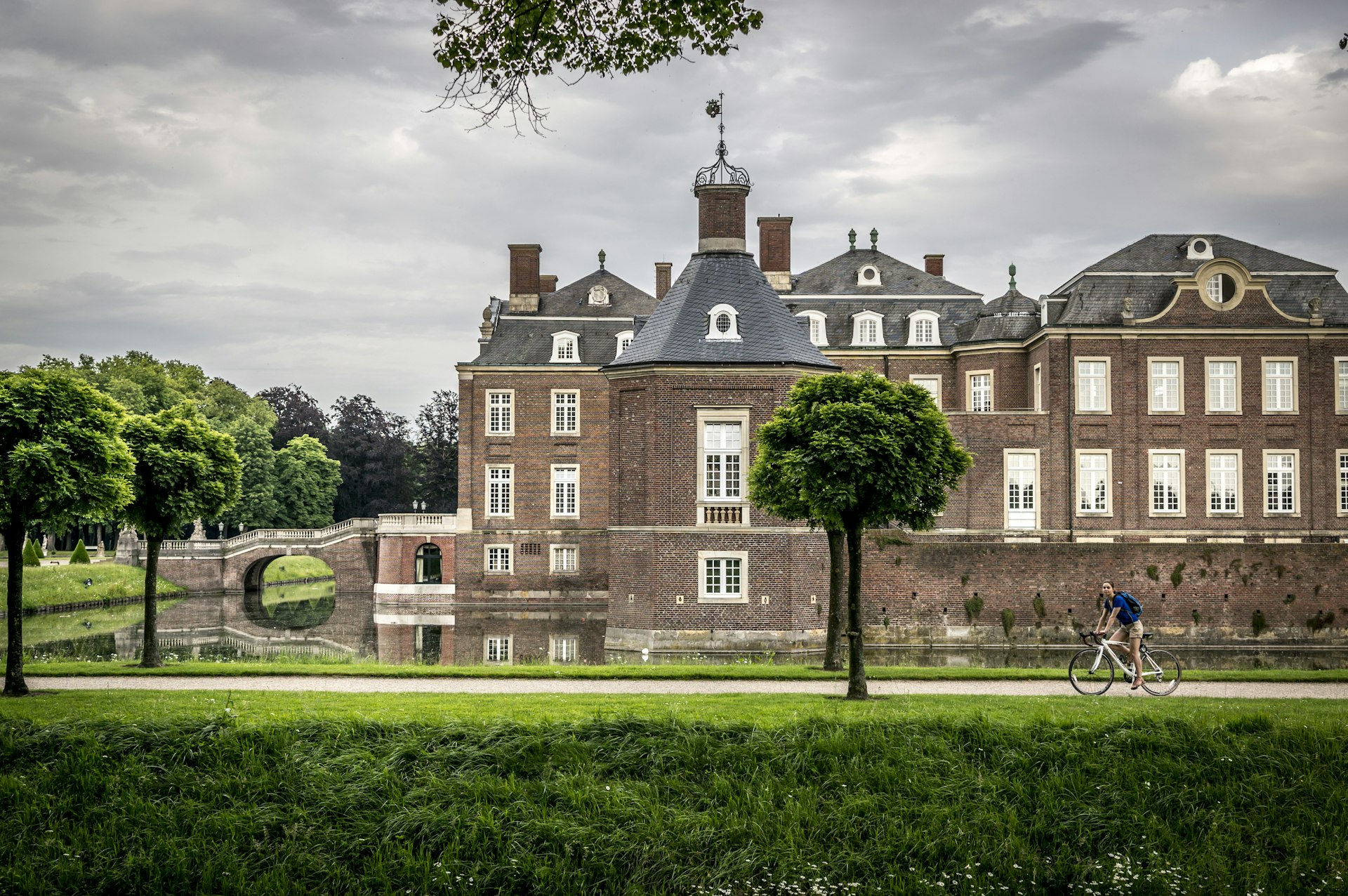 A cyclist rides a bike along a path beside a vast castle complex