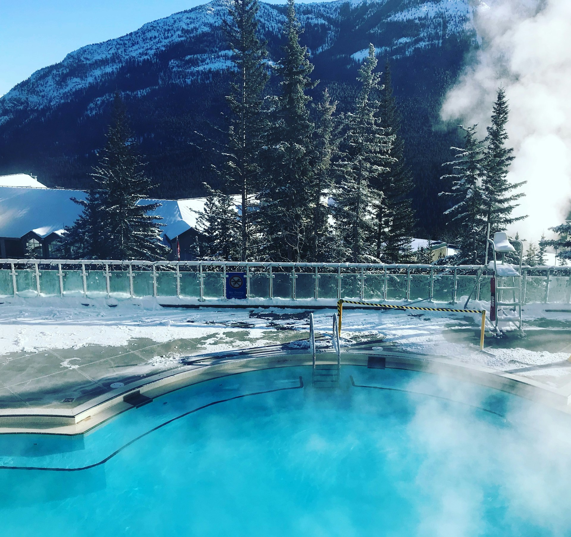 A steaming hot pool overlooking a snowy mountain range at Banff Upper Hot Springs