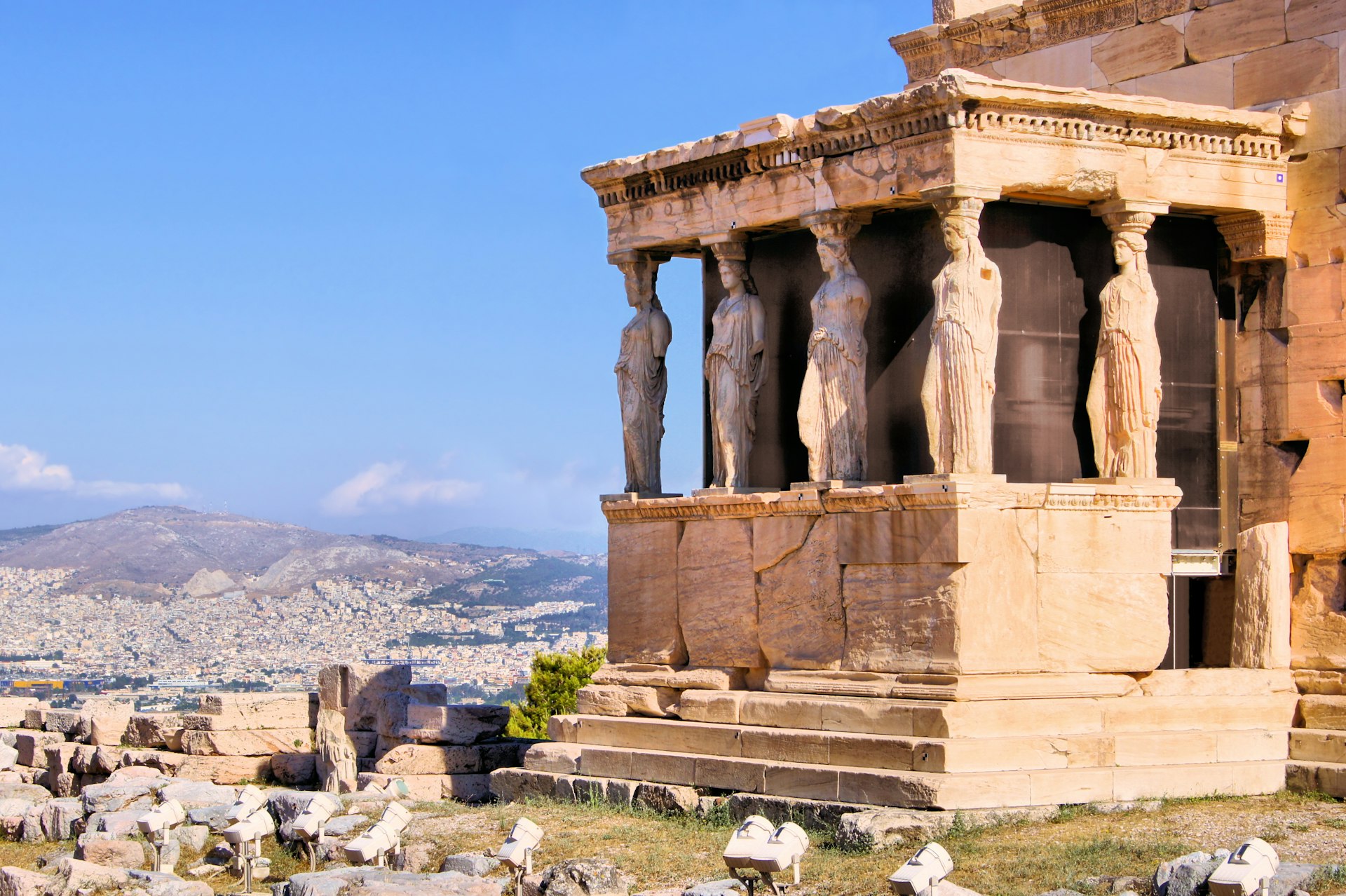 Giant statues on the side of an ancient building high on a hill overlooking a city