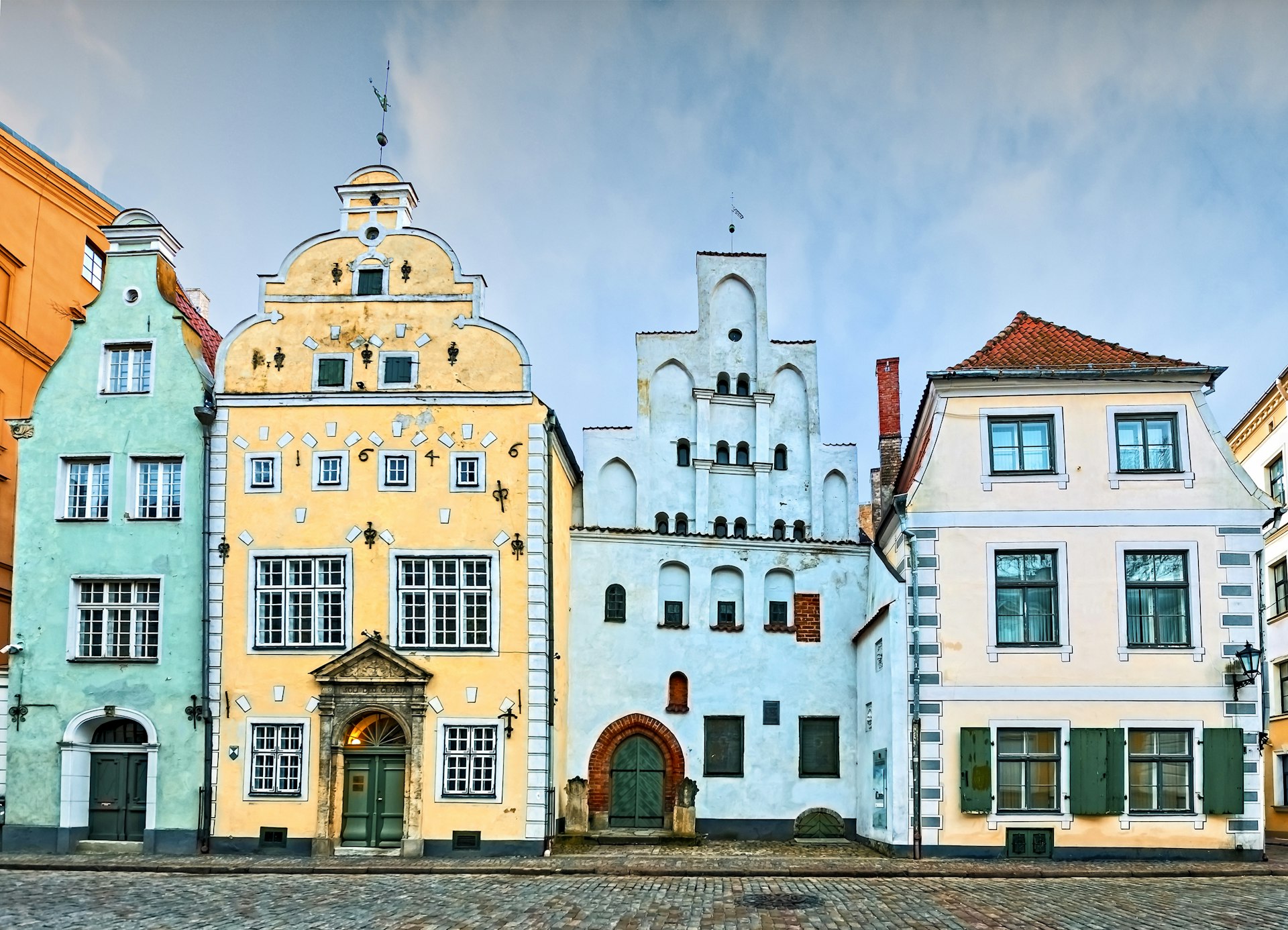 A row of pastel-colored medieval buildings at the edge of a city square