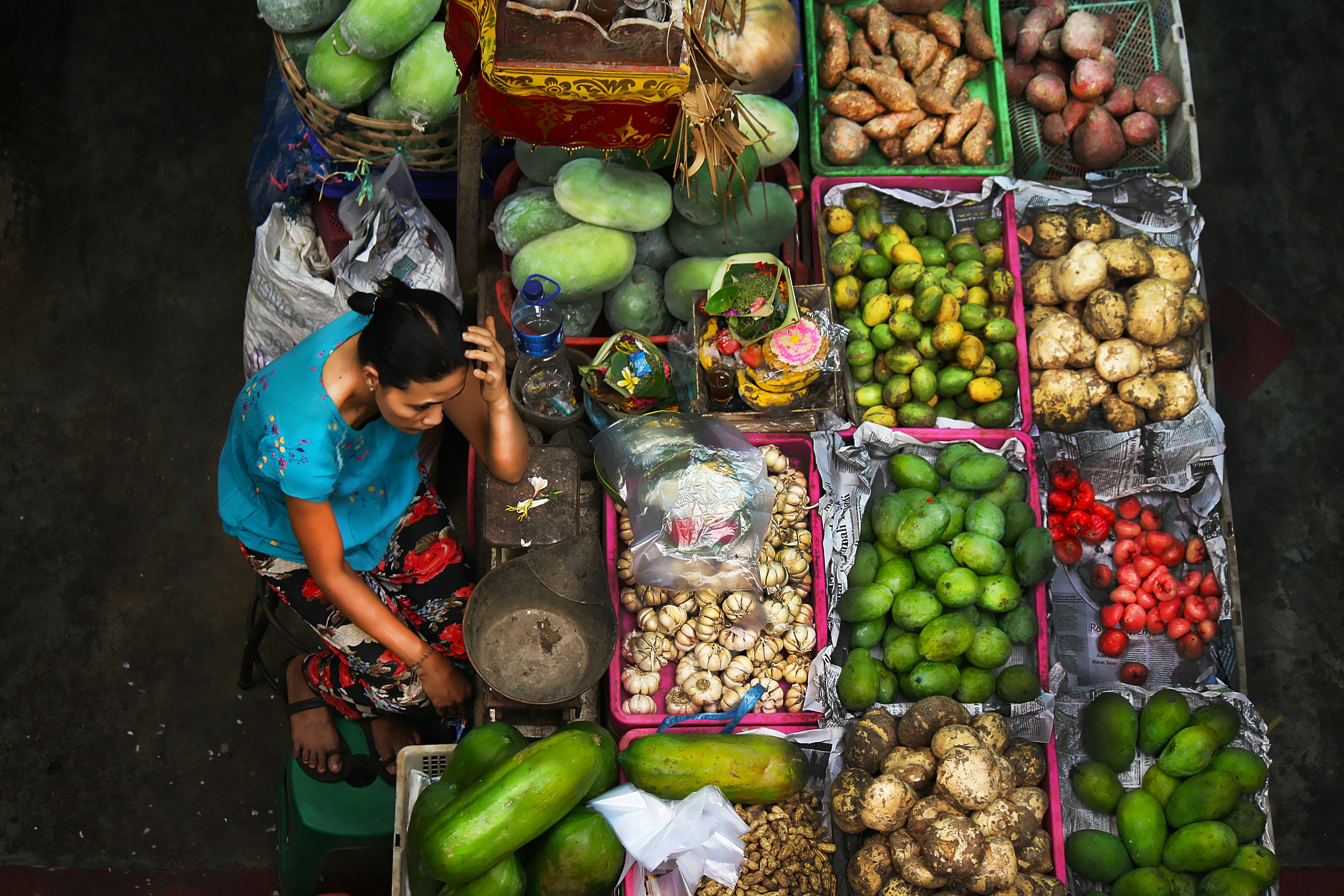 A high-angle view of a woman selling fruit and vegetables at a stall in Pasar Badung market, Denpasar, Bali, Indonesia