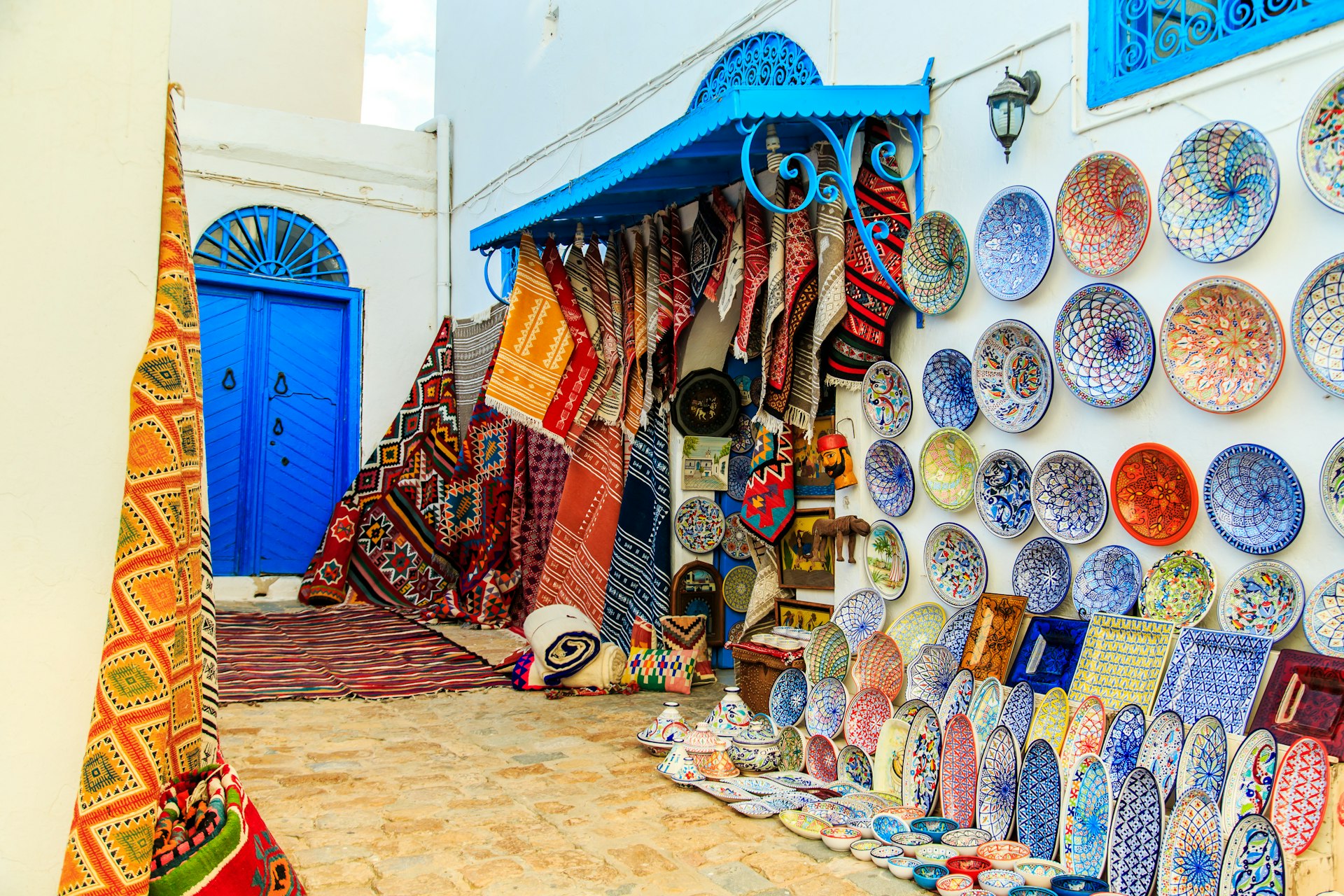 Souvenir earthenware and carpets on display at a Tunisian market.