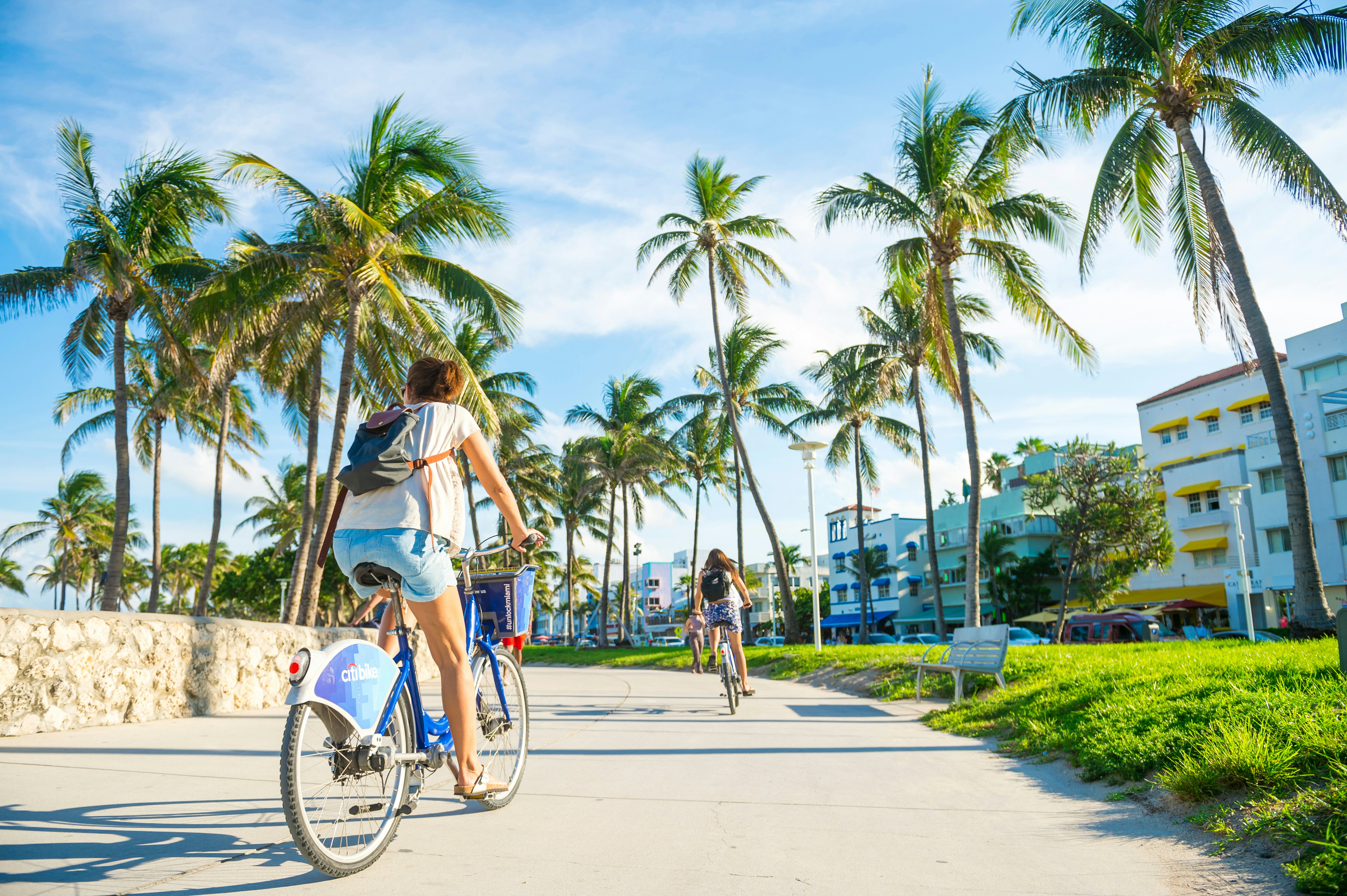 A young woman rides along the Ocean Drive promenade on a Citibike, Lummus Park