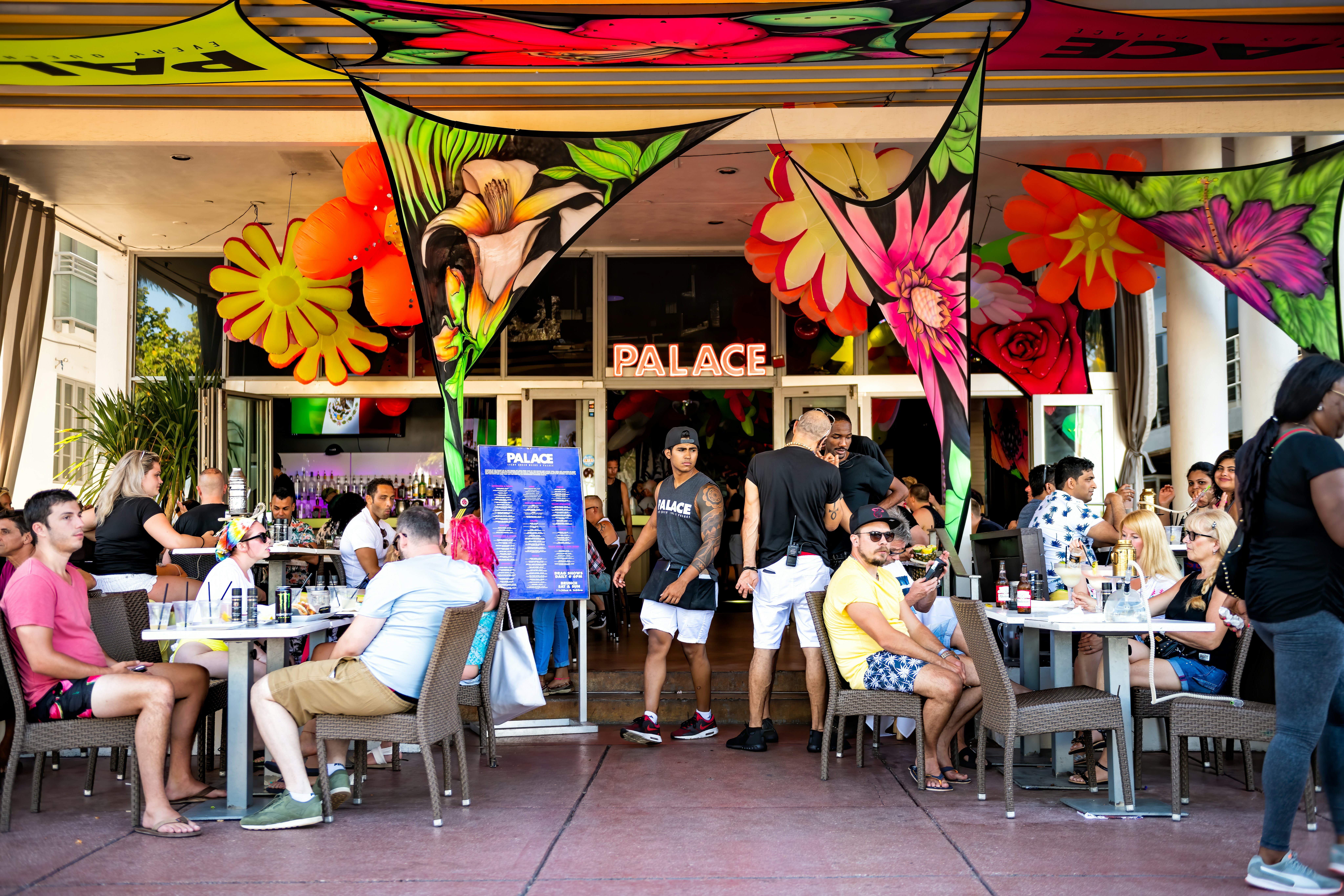 People sitting eating drinking at The Palace bar restaurant in Florida Art Deco district of South Beach on Ocean drive in summer