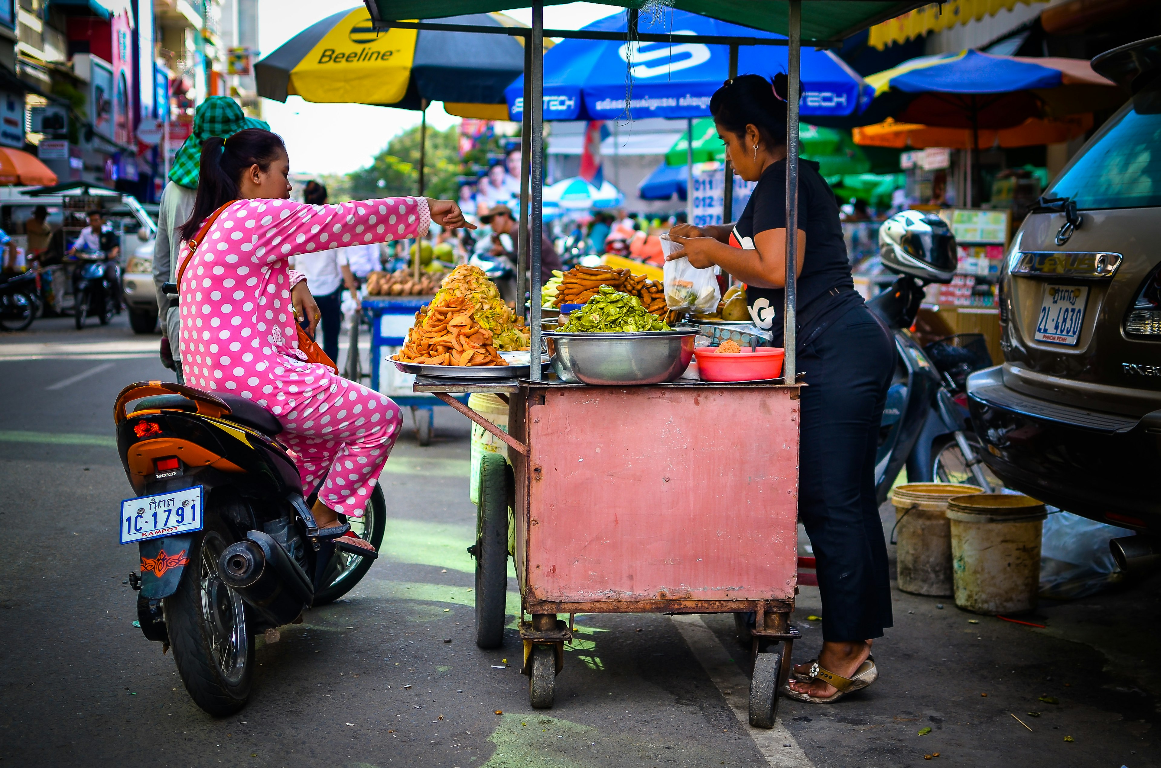 Women on a scooter eating street food in Phnom Penh, Cambodia