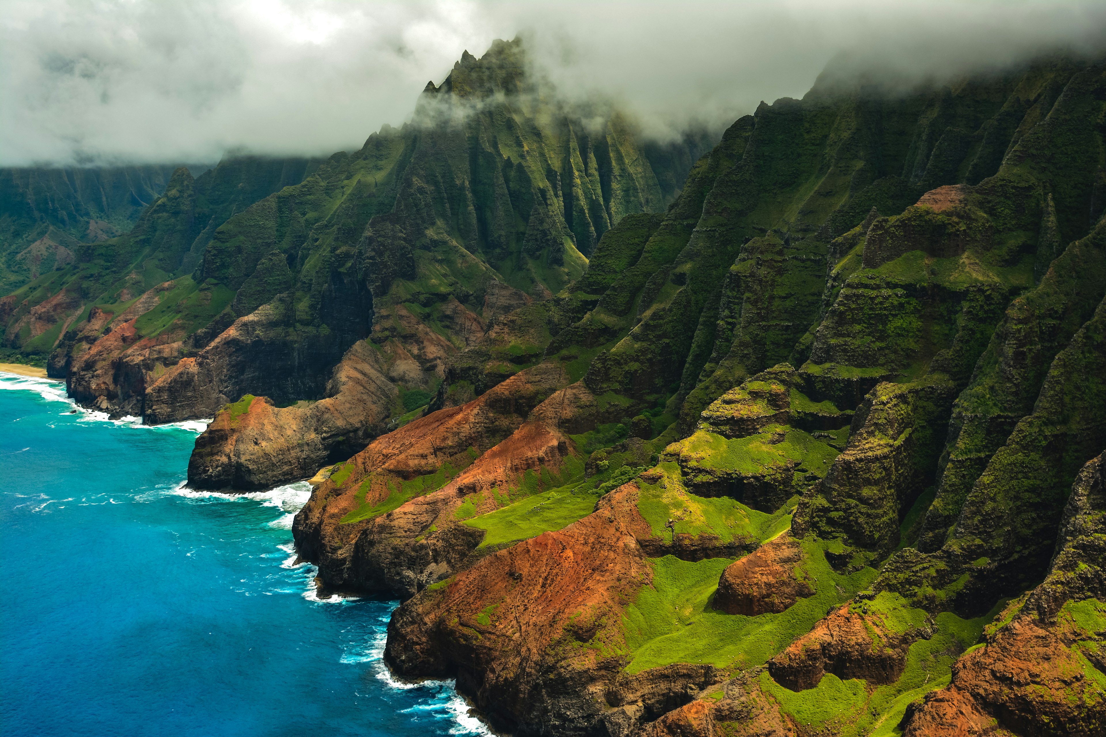 The rugged Na Pali Coast from a helicopter, with clouds overhead