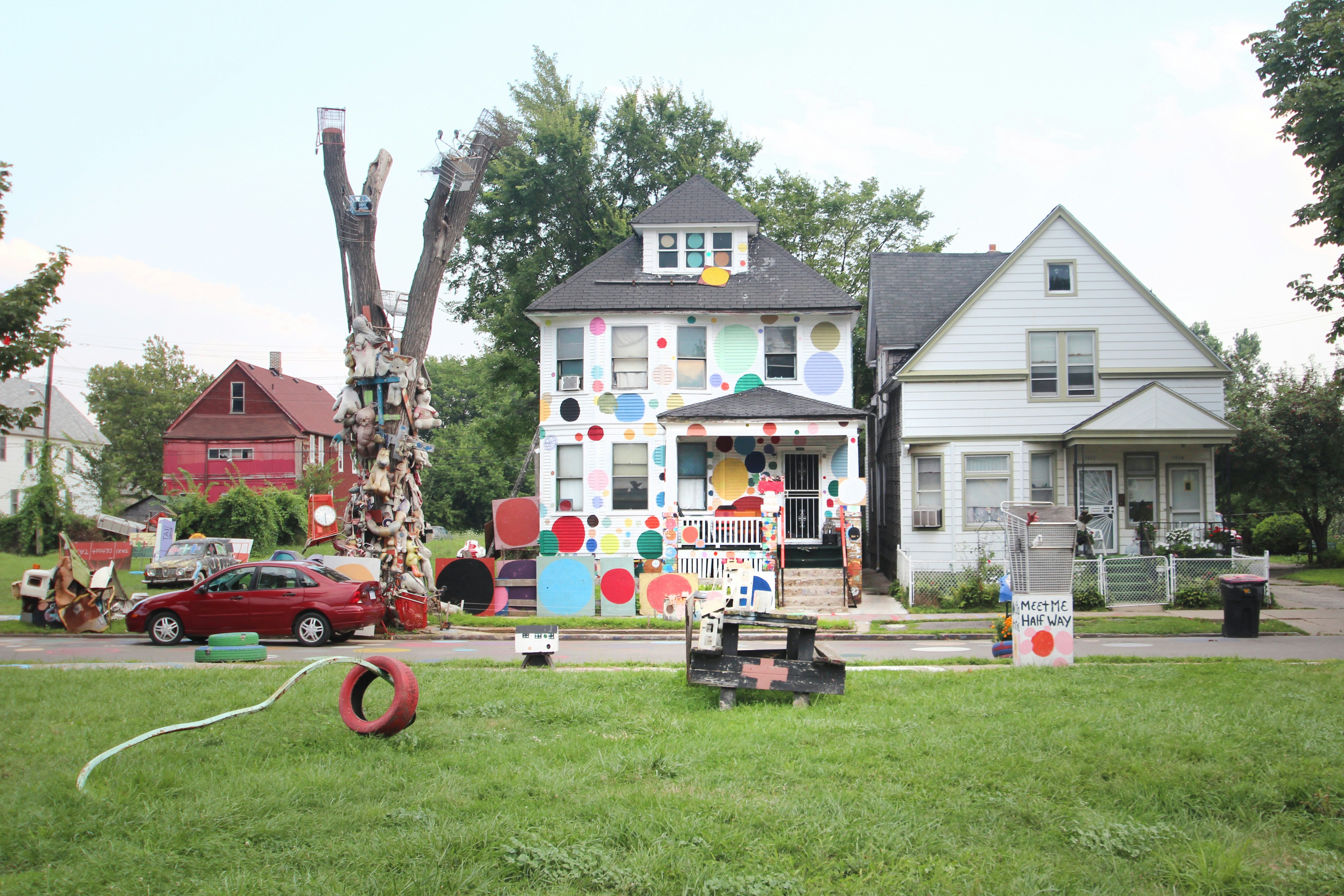 The exterior of a white building that has been decorated with large colorful circles and spots as part of the Heidelberg Project in Detroit, Michigan