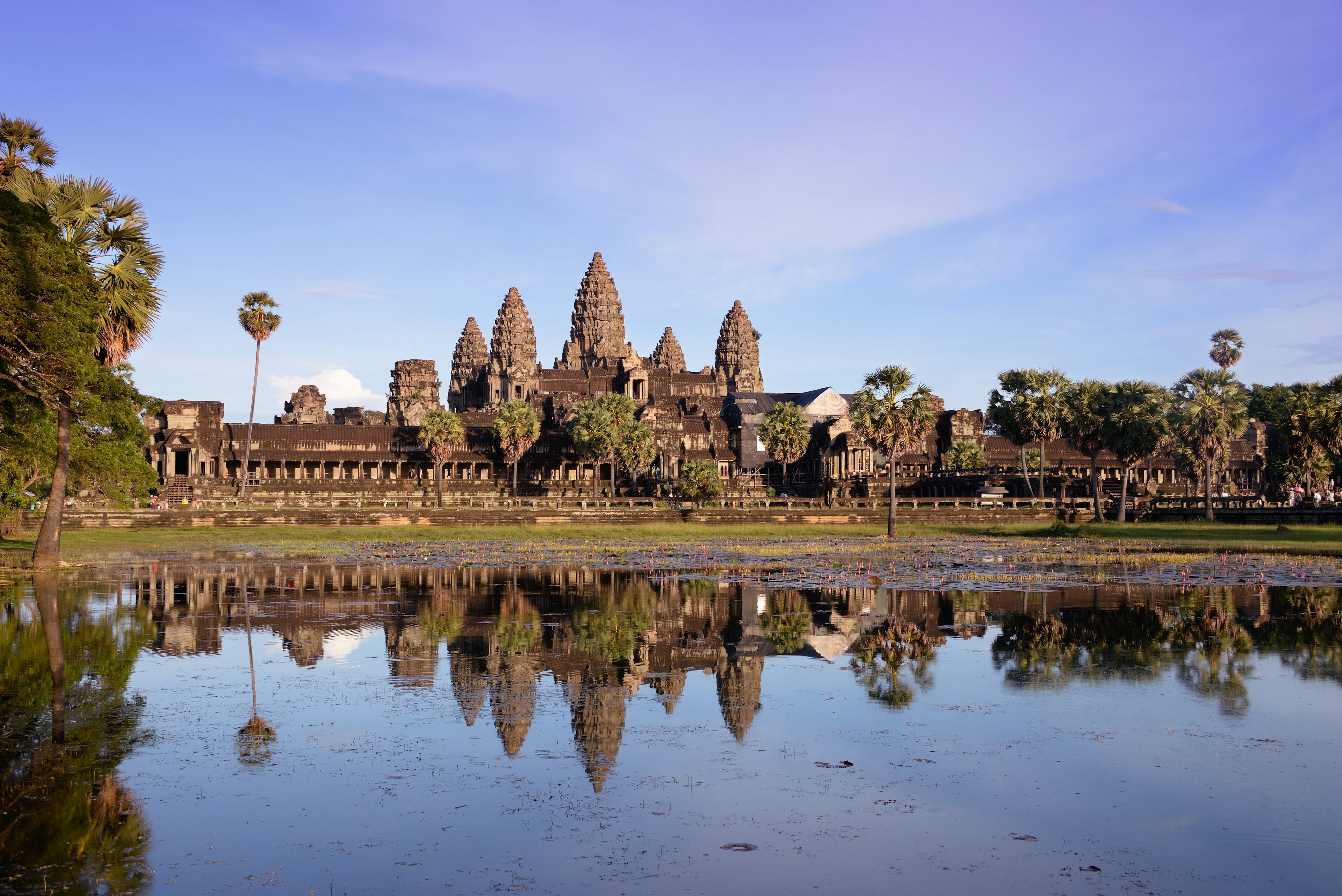 A large temple complex with five domed towers is reflected in a lake