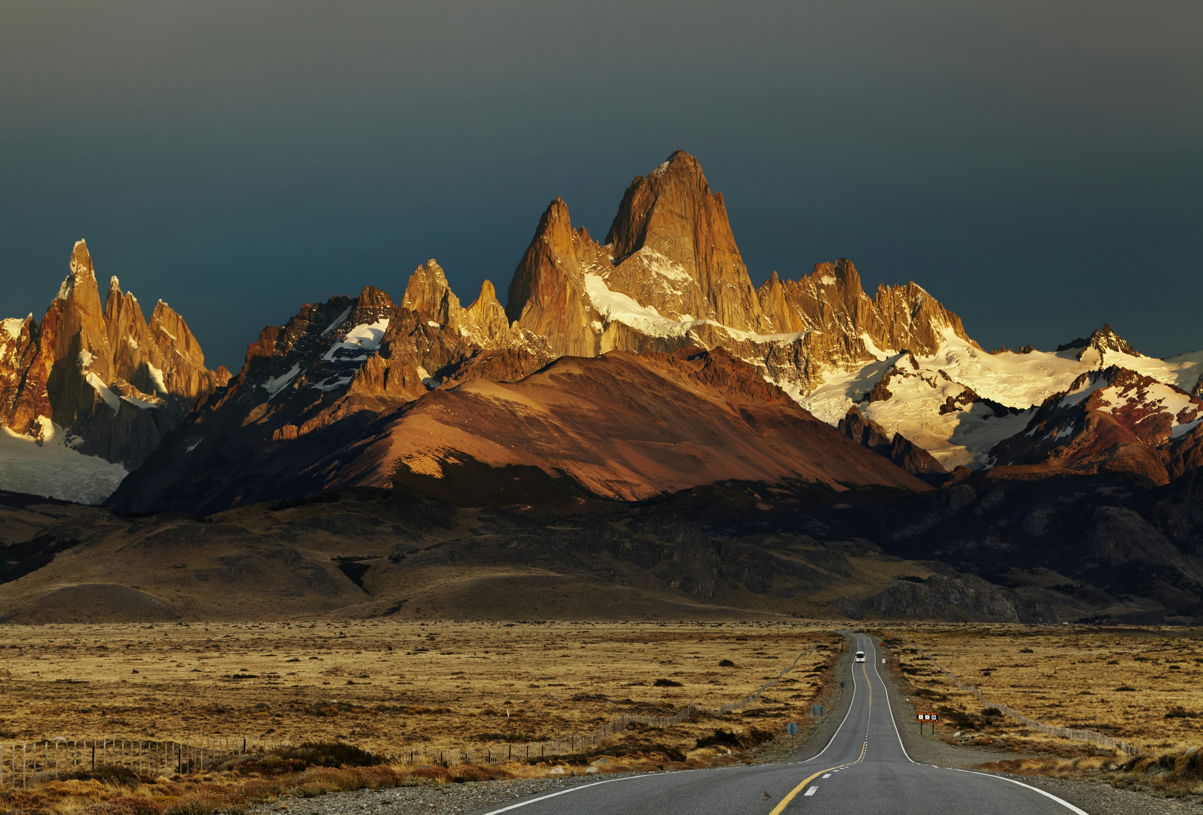 Empty road leading to very pointy mountain peaks